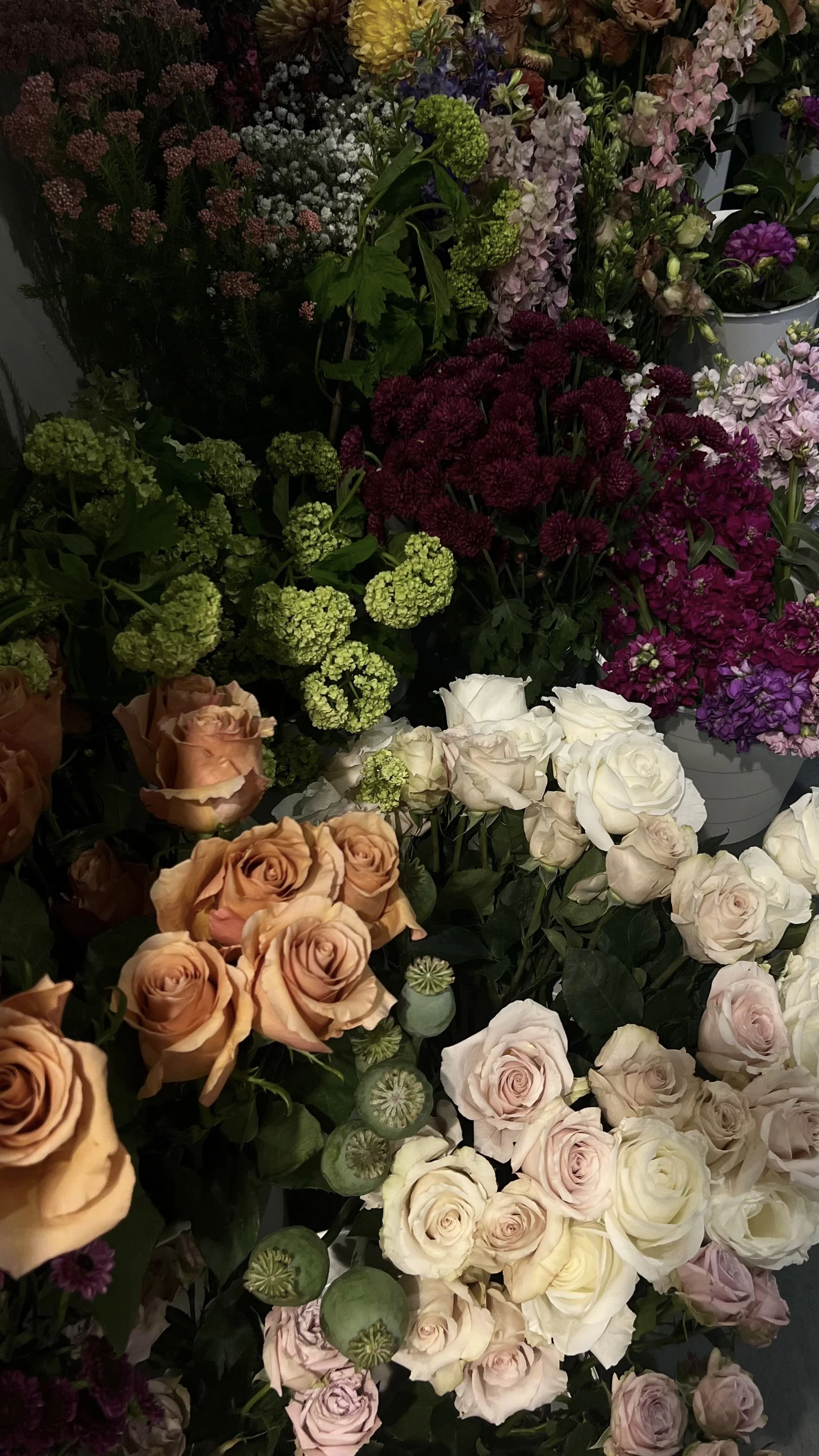 Various fresh flowers including roses, hydrangeas, and asters in different colors arranged in a display.