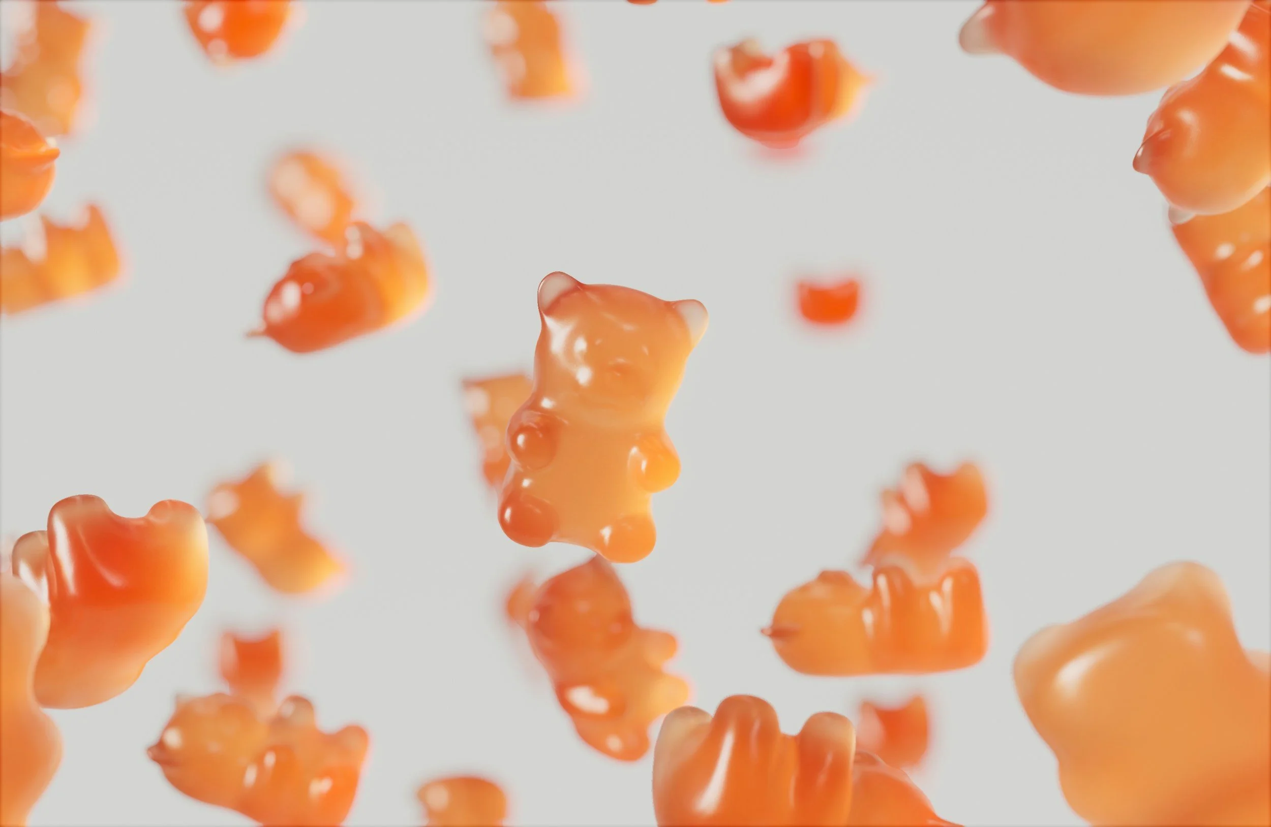 Orange gummy bears falling against a white background.