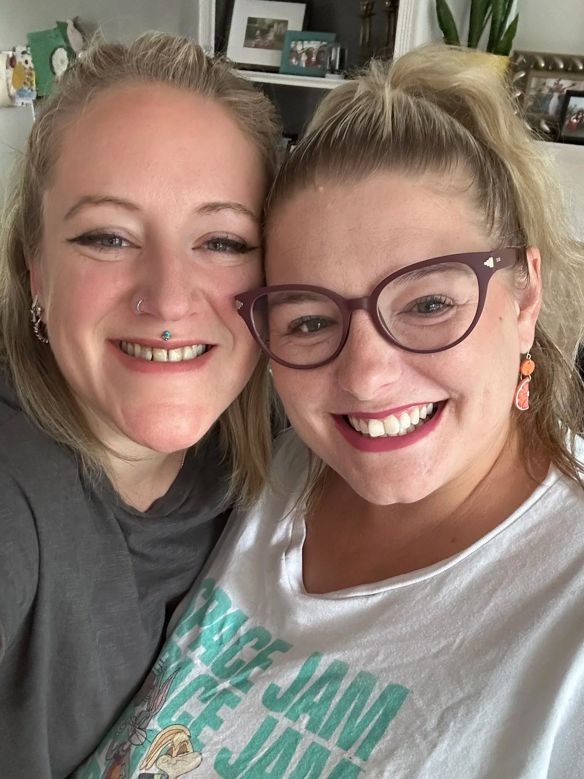 Two women smiling and taking a close-up selfie indoors.