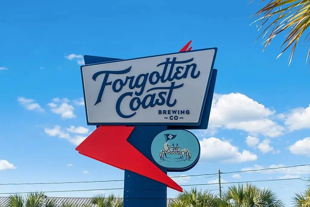 Sign for Forgotten Coast Brewing Co. with a red arrow pointing left, and an illustration of two crabs at a table with a pirate hat under a partly cloudy sky.