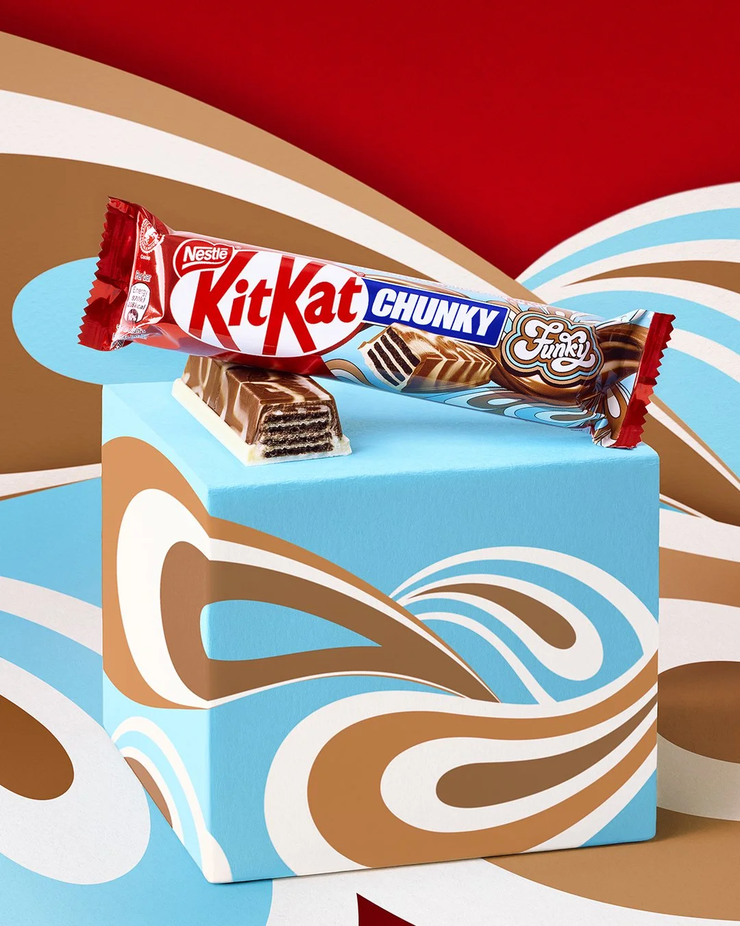 A KitKat Chunky Funky candy bar resting on a colorful box with a swirl pattern of blue, white, brown, and red background.