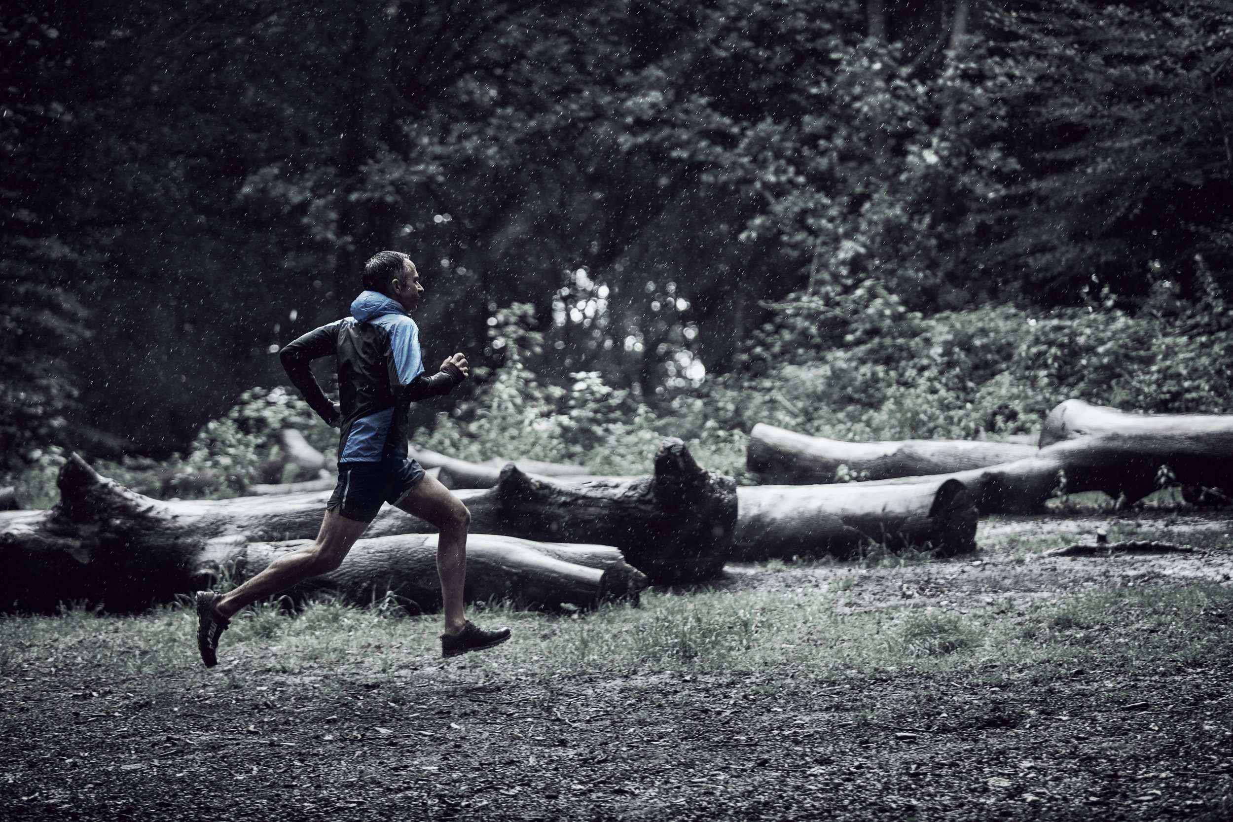 A person running in a snowy forest during rainfall.