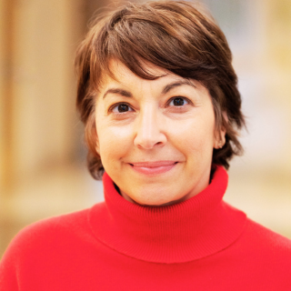 Portrait of a woman with short brown hair wearing a red turtleneck sweater, smiling at the camera.