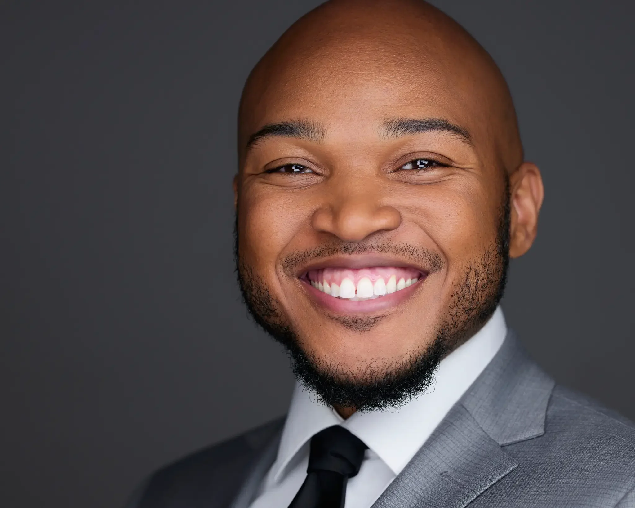 Smiling man in formal suit with a gray background