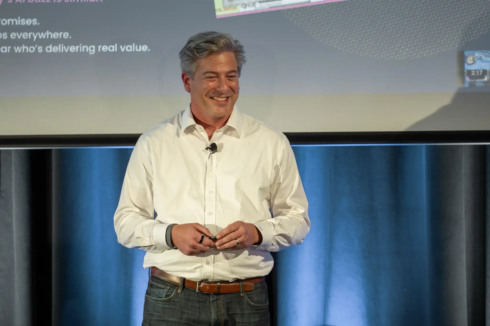 presenter smiling as he presents information on the projection behind him