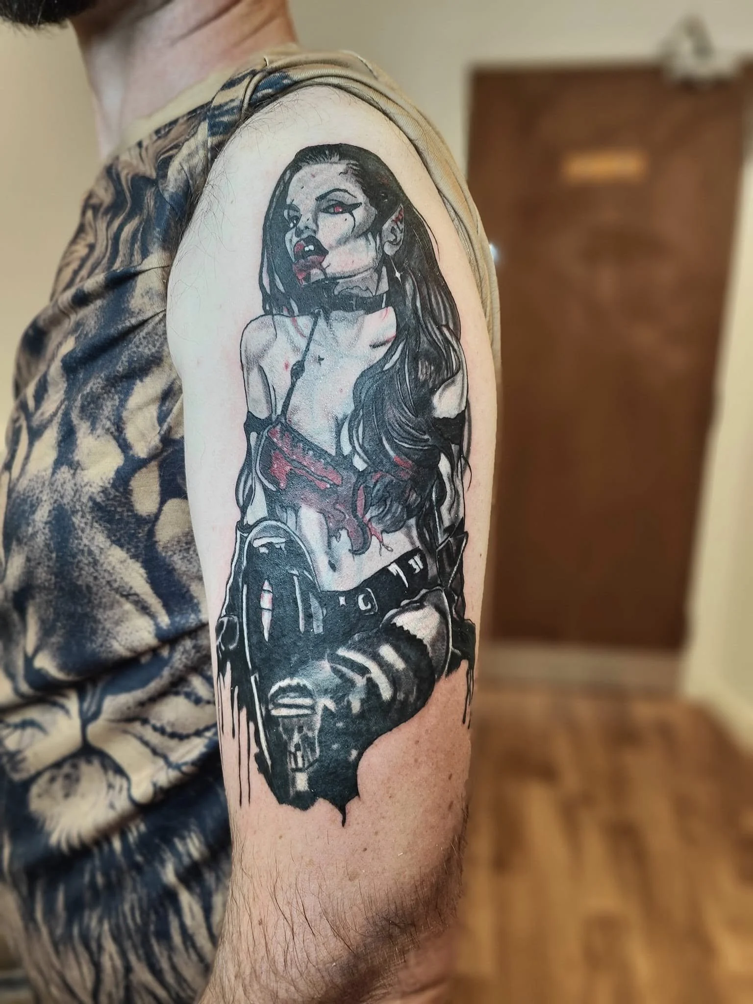 Tattoo cover on person's upper arm depicting a dark-haired  vampire woman with red eyes, red mouth, and gothic attire in black, gray, and red colors.