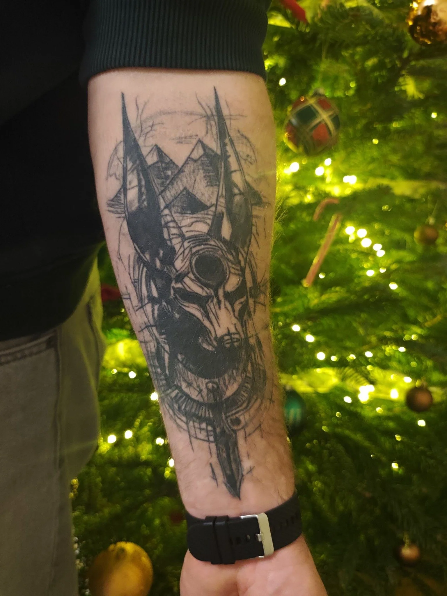 Tattoo of Anubis with Egyptian background on person's forearm.