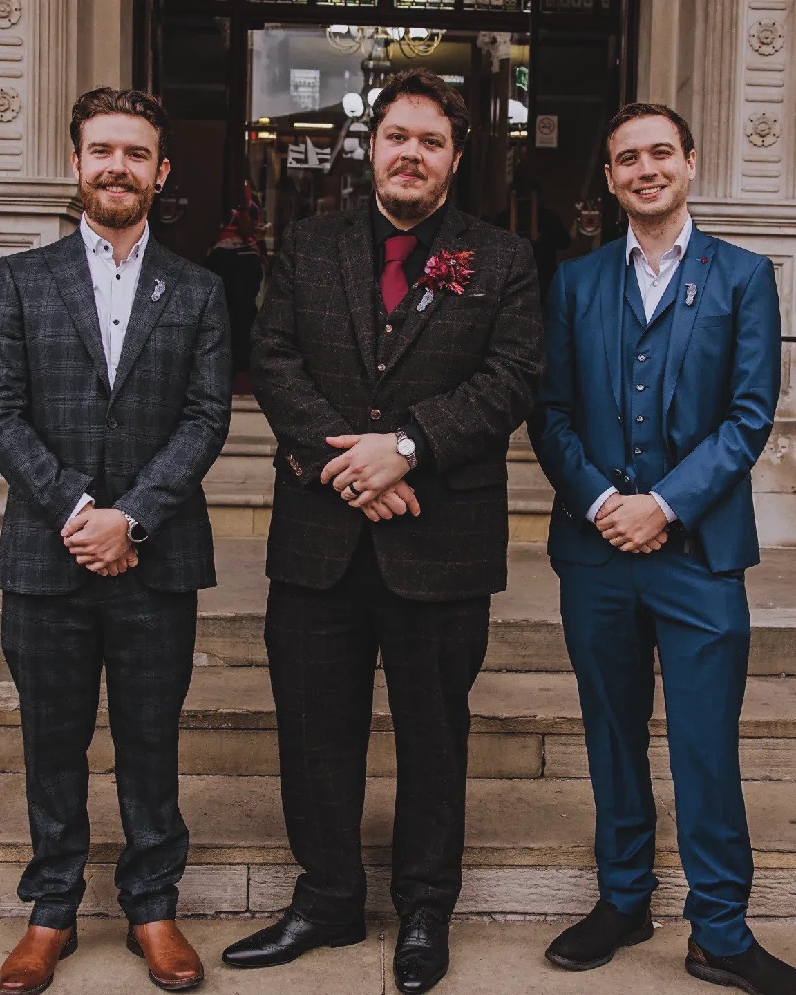 Three men in suits standing on steps outside a building, posing for a photo.