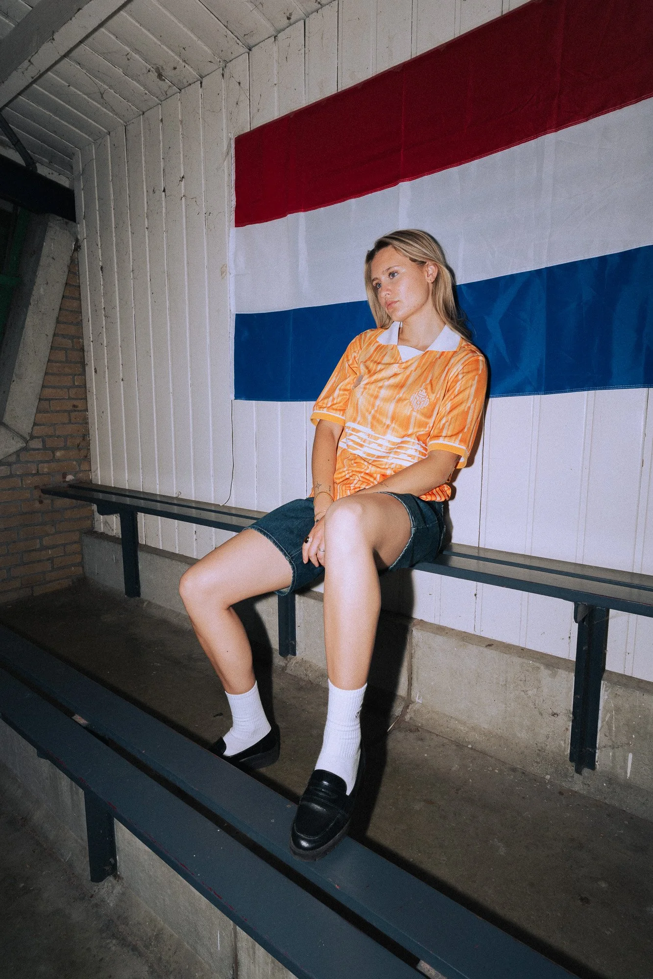 Foto van model op een bankje met een Nederlandse vlag op de achtergrond