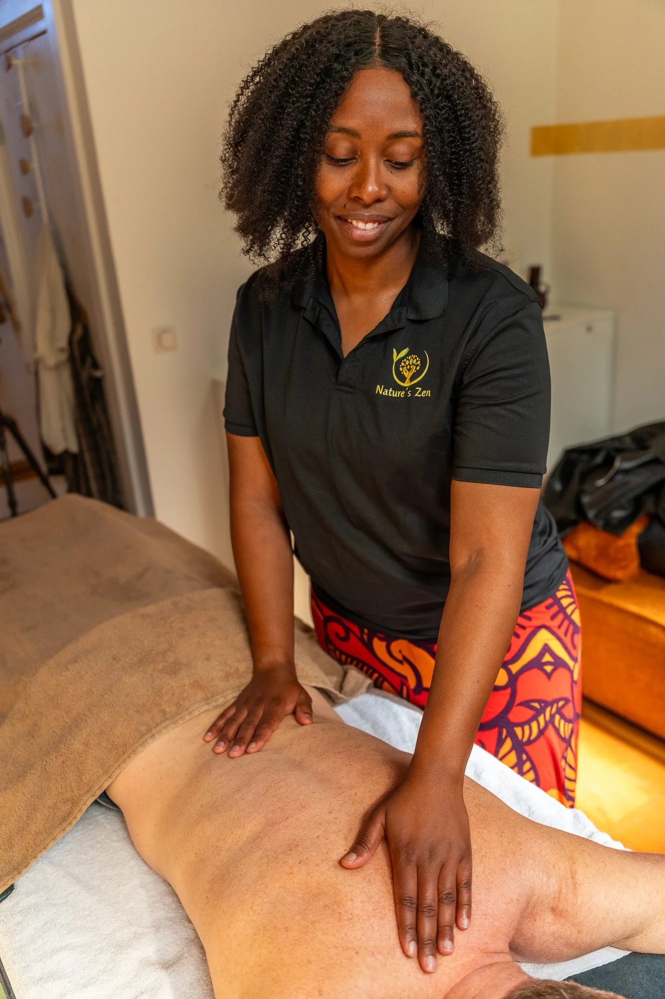 Vrouw geeft een massage aan een man die op zijn buik ligt, in een ontspanningsruimte.