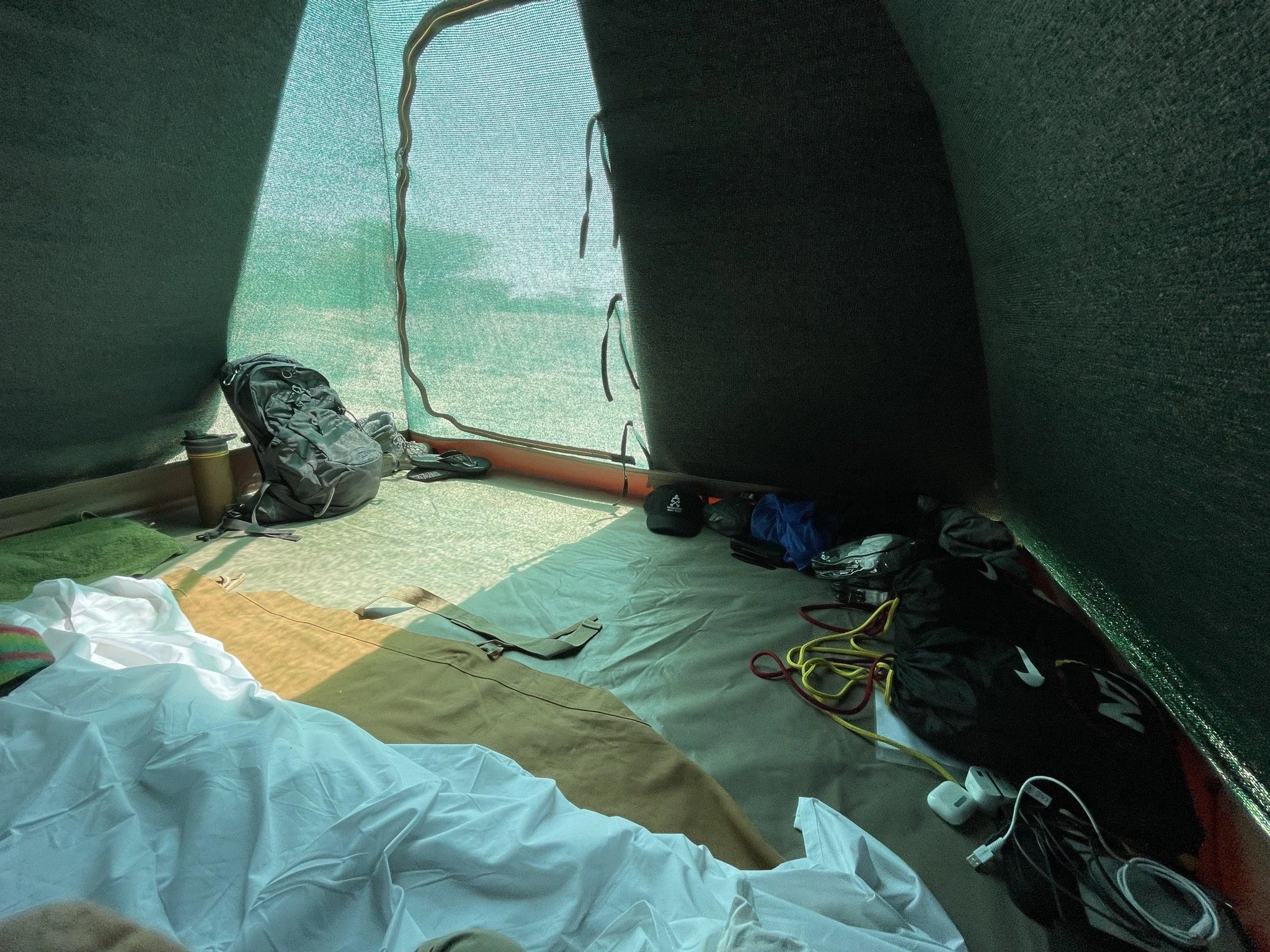 Climbing tent interior with sleeping gear, backpack, water bottle, and climbing ropes.