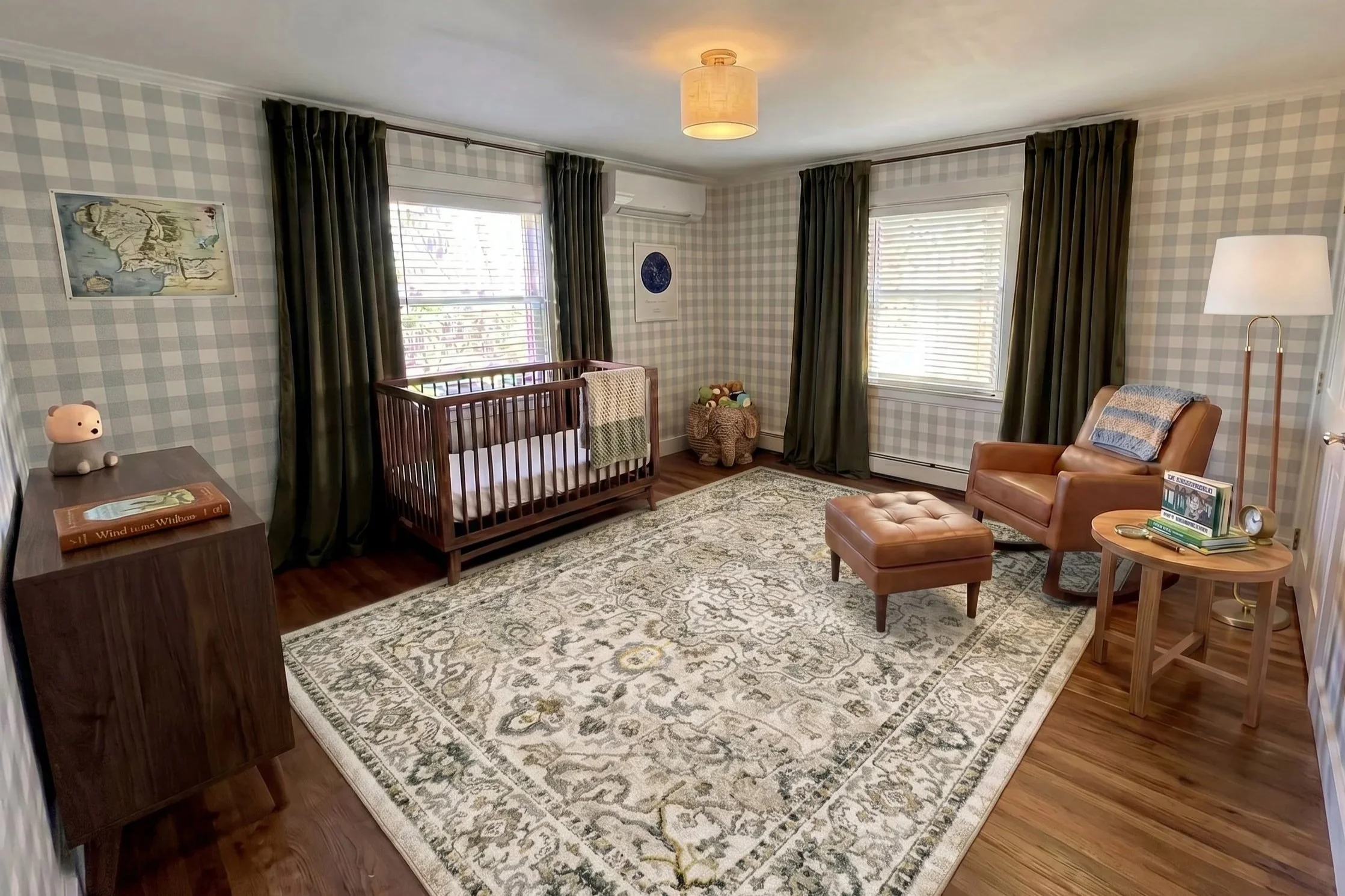 Nursery with checkered wallpaper, dark green curtains, a wooden crib, a plush toy basket, a tan armchair, an ottoman, a floor lamp, framed artworks, and a patterned area rug.