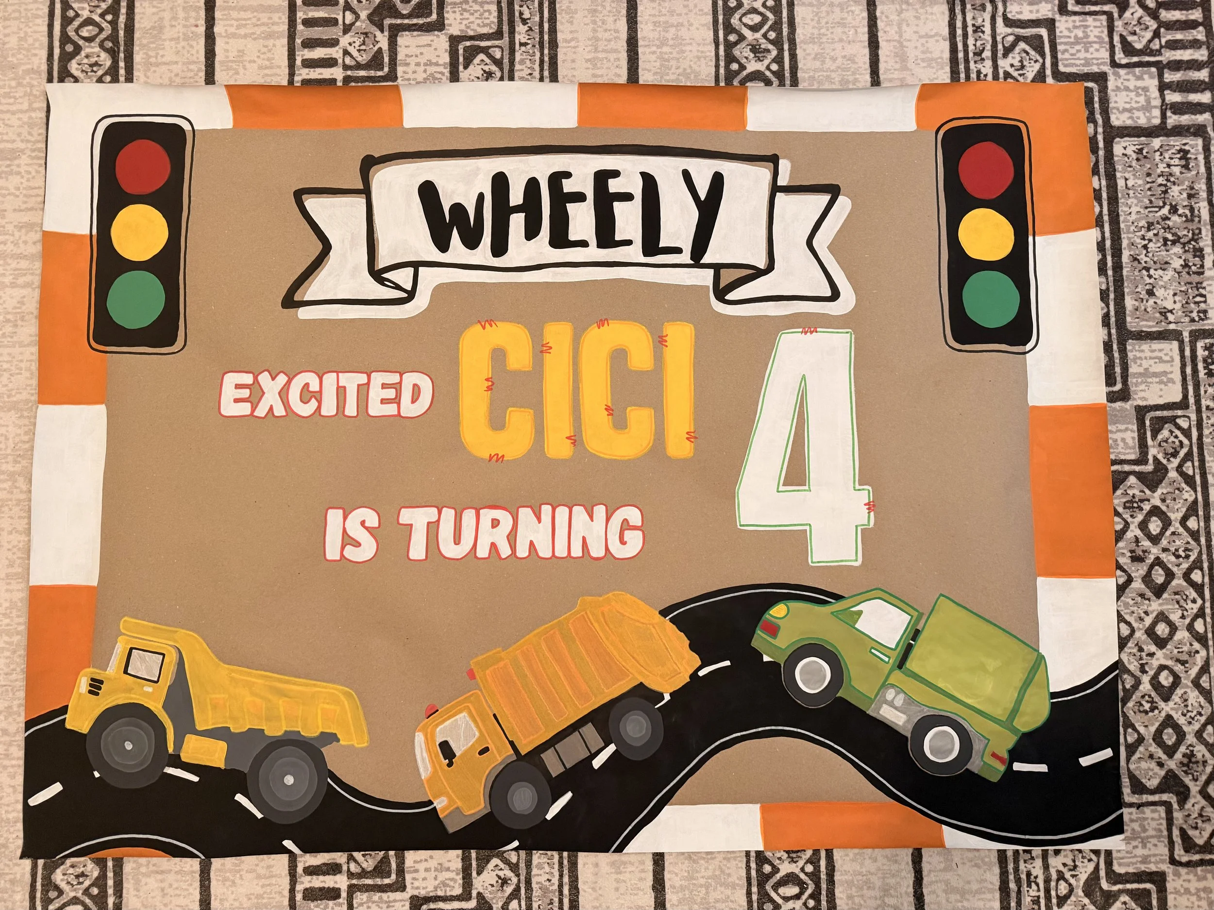 Decorative poster with traffic lights, construction trucks, and the message 'Wheely Que' with the phrase 'Excited' and the number '4' indicating age.