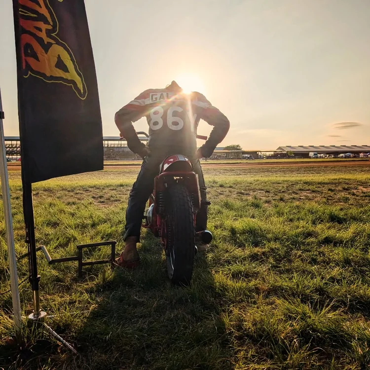 Rider with a race bike at sunset in the pits
