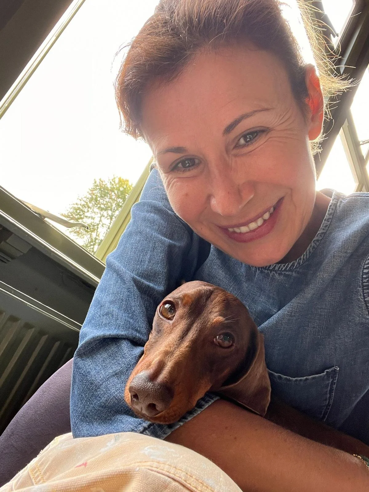 Portrait of young girl smiling holding a brown Dachshund dog