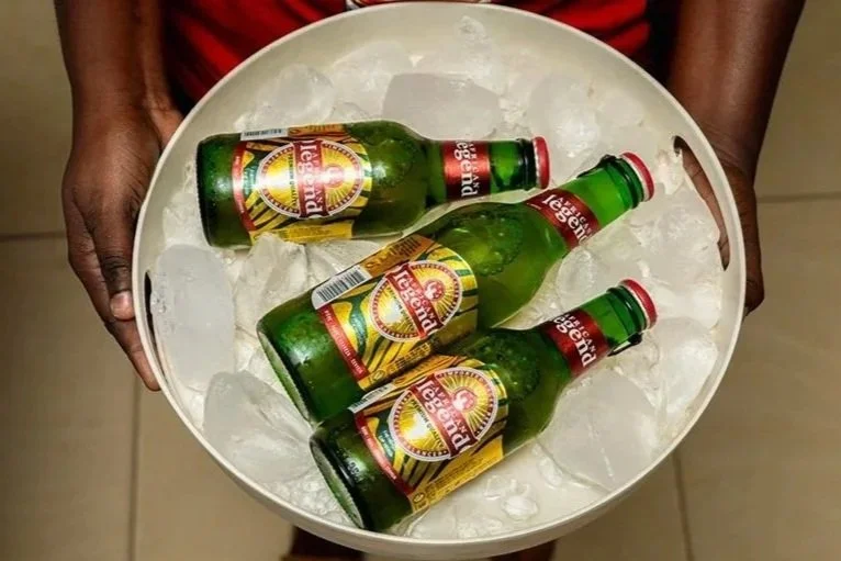 Person holding a white bowl filled with ice and four bottles of beer.