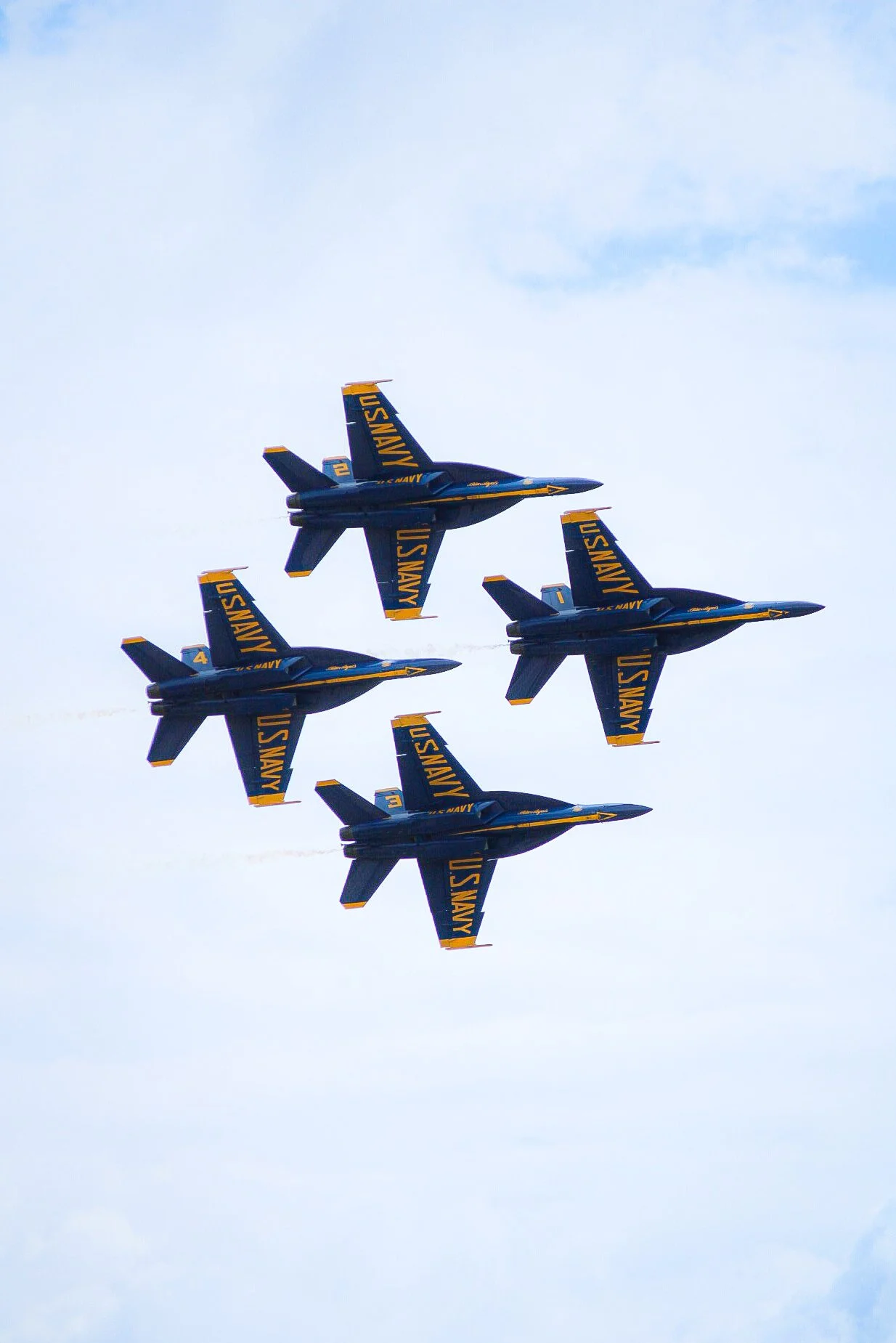 Four U.S. Navy Blue Angels fighter jets flying in tight formation against the sky.