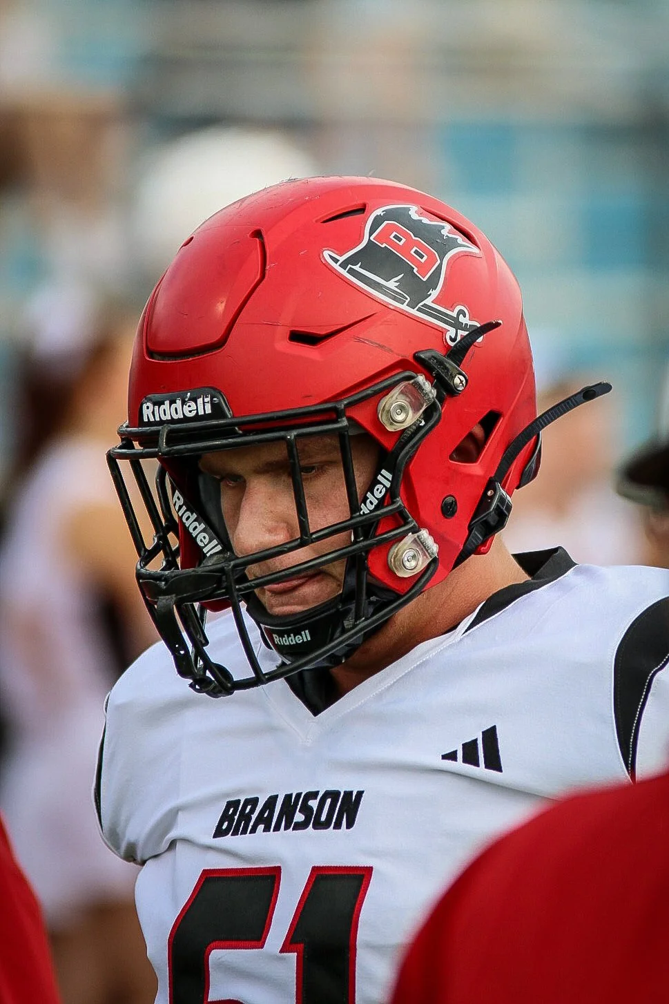 Close-up of an American football player wearing a red helmet with a logo, black faceguard, white jersey with black and red accents, and the number 11. The jersey has the word 'BRANSON' on it.