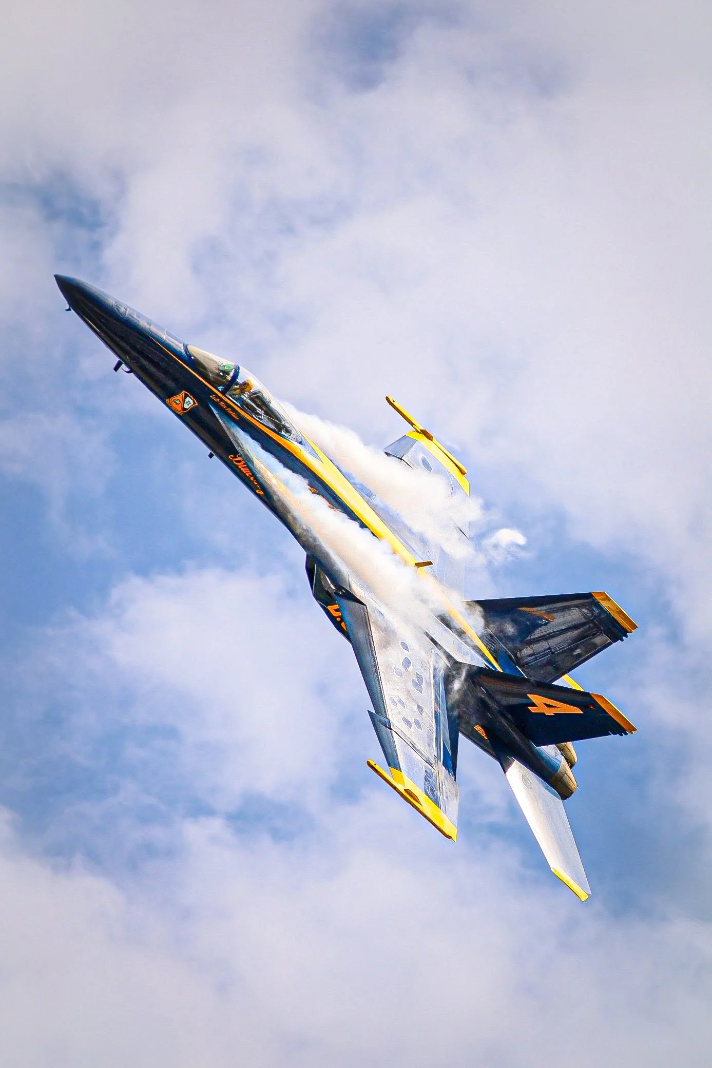 An aircraft performing a steep banking maneuver in the sky, leaving a trail of white vapor behind.