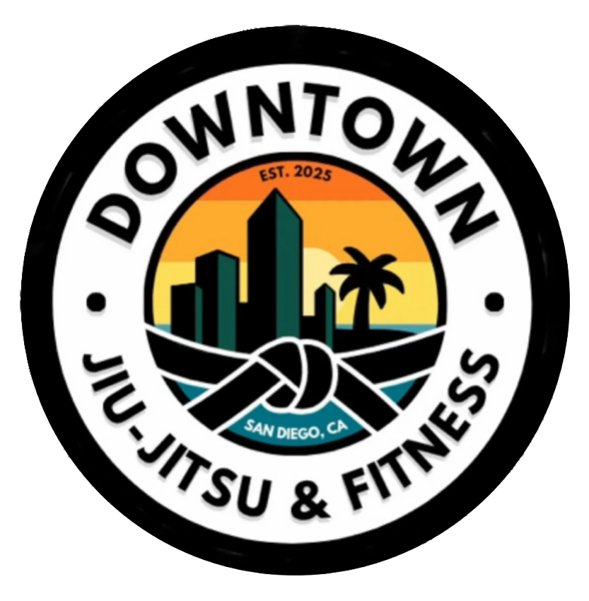 A circular logo for Downtown Ju-Jitsu & Fitness in San Diego, CA, featuring a city skyline, palm tree, sunset, and a knotted rope, with the text 'EST. 2025'.