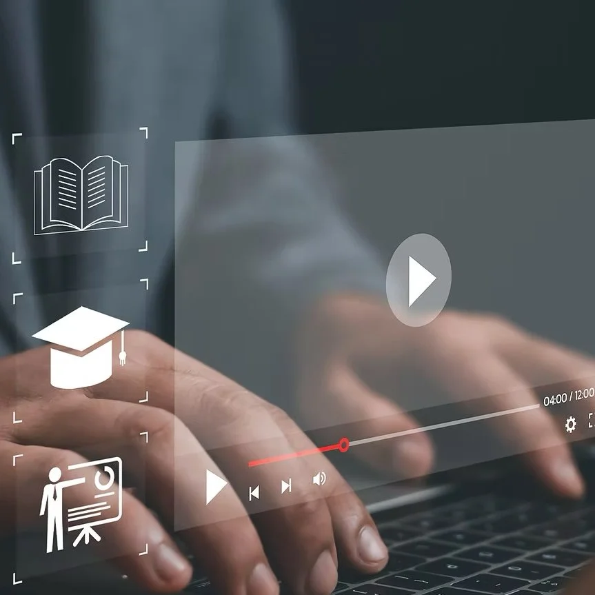 Close-up of a person using a laptop with overlaid icons representing education, reading, and online learning, including a book, graduation cap, and a person giving a presentation.