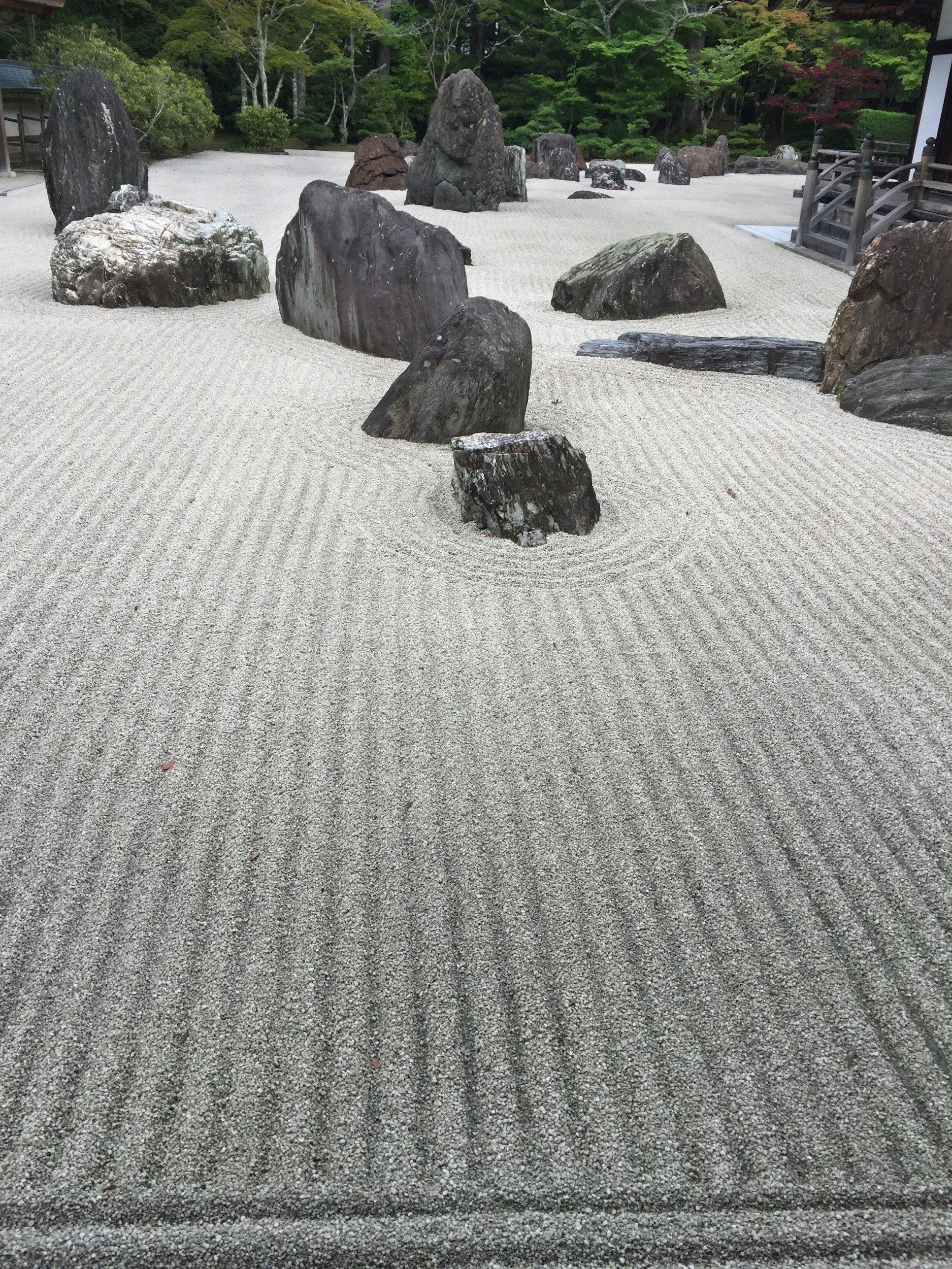 A Japanese Zen garden with several large rocks placed on raked white gravel, symbolic of a calmness and sense of balance, as opposed to feelings of stress and burnout.