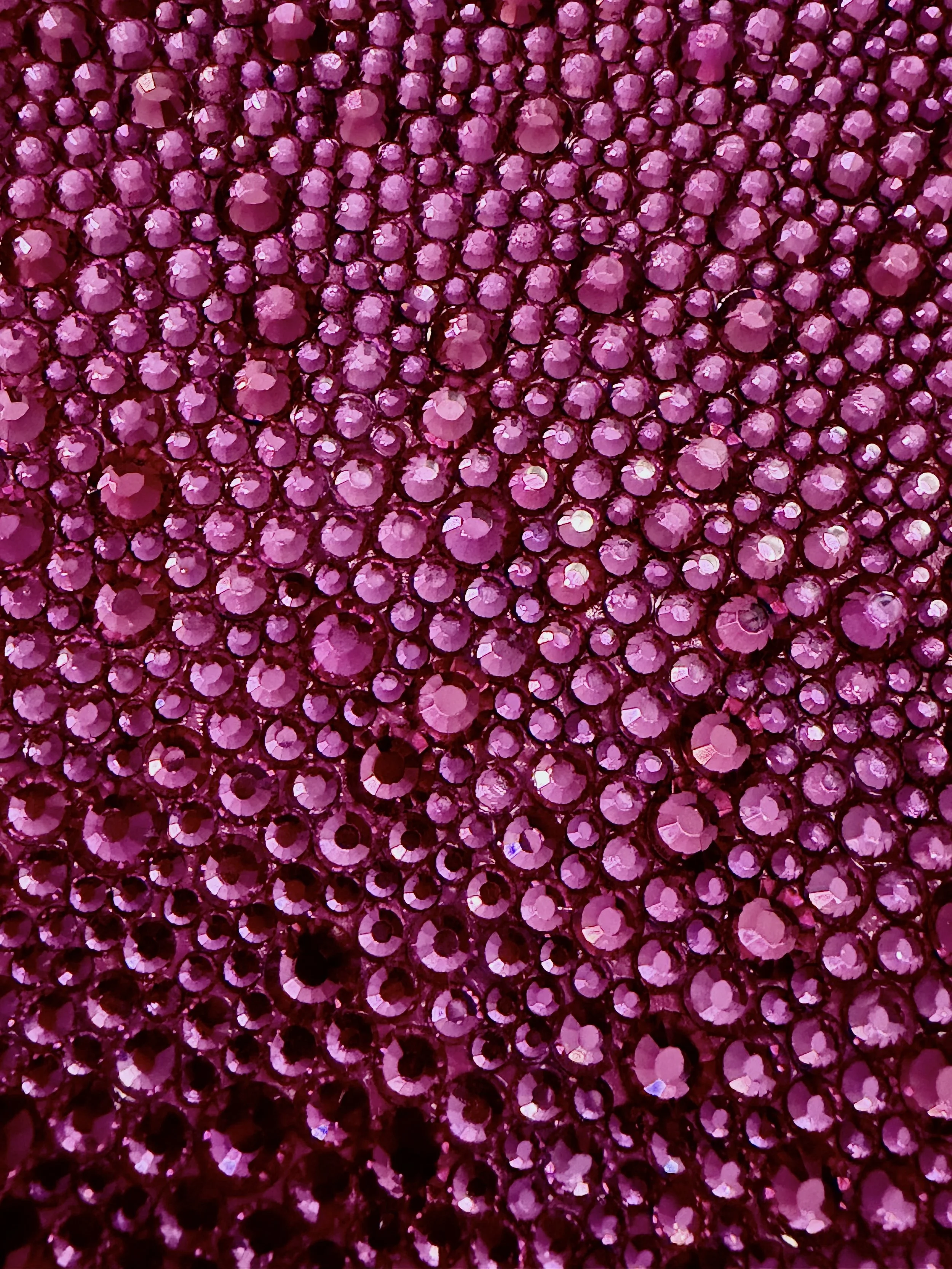 Macro detail of "Lust" by Artwork by AMS: A dense, monochromatic field of hand-placed magenta glass rhinestones in four sizes. The close-up highlights the faceted surfaces of the stones and the intricate, repetitive texture of the sculptural panel.