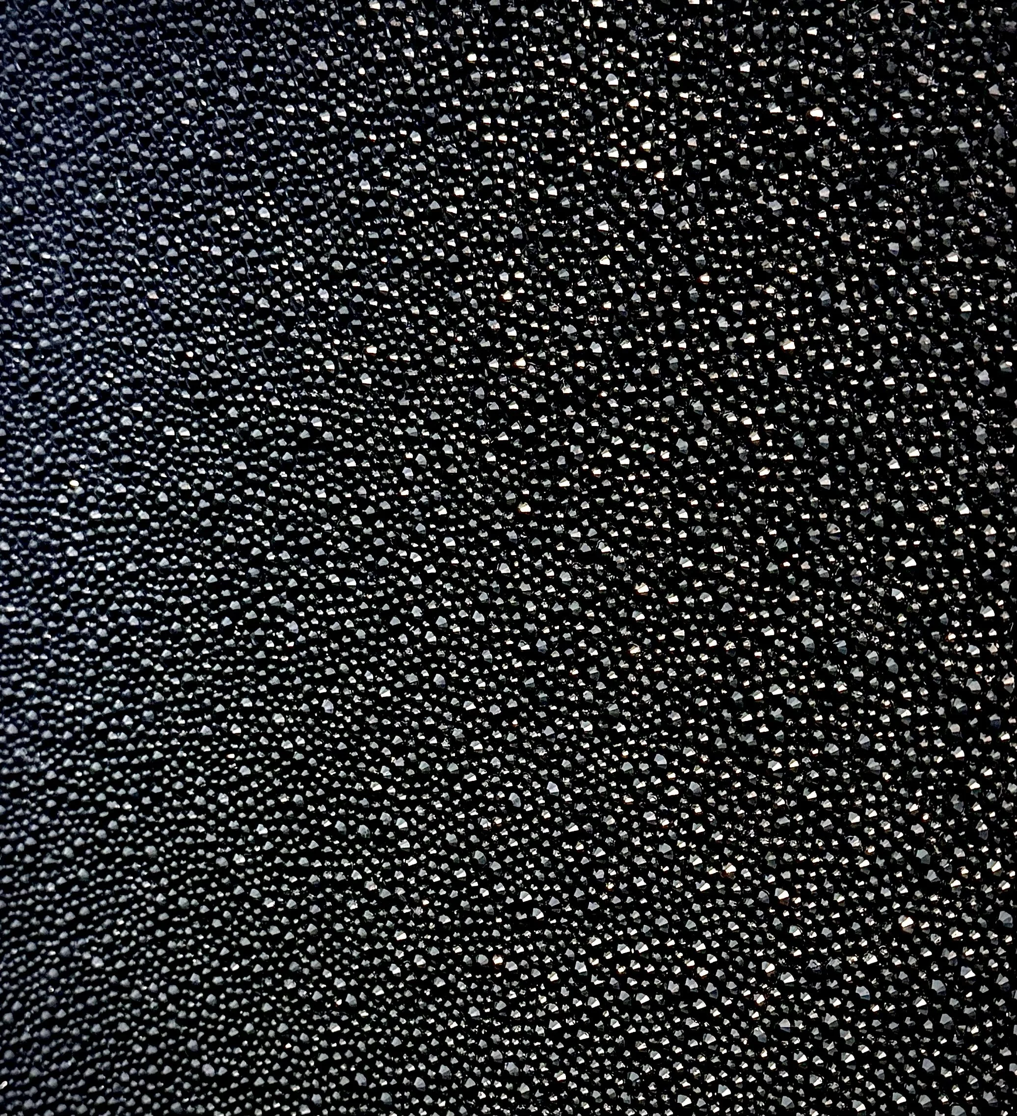 Macro detail of Pressure (2025). Close-up of black glass rhinestones, creating a uniform, dark texture with high-contrast light.