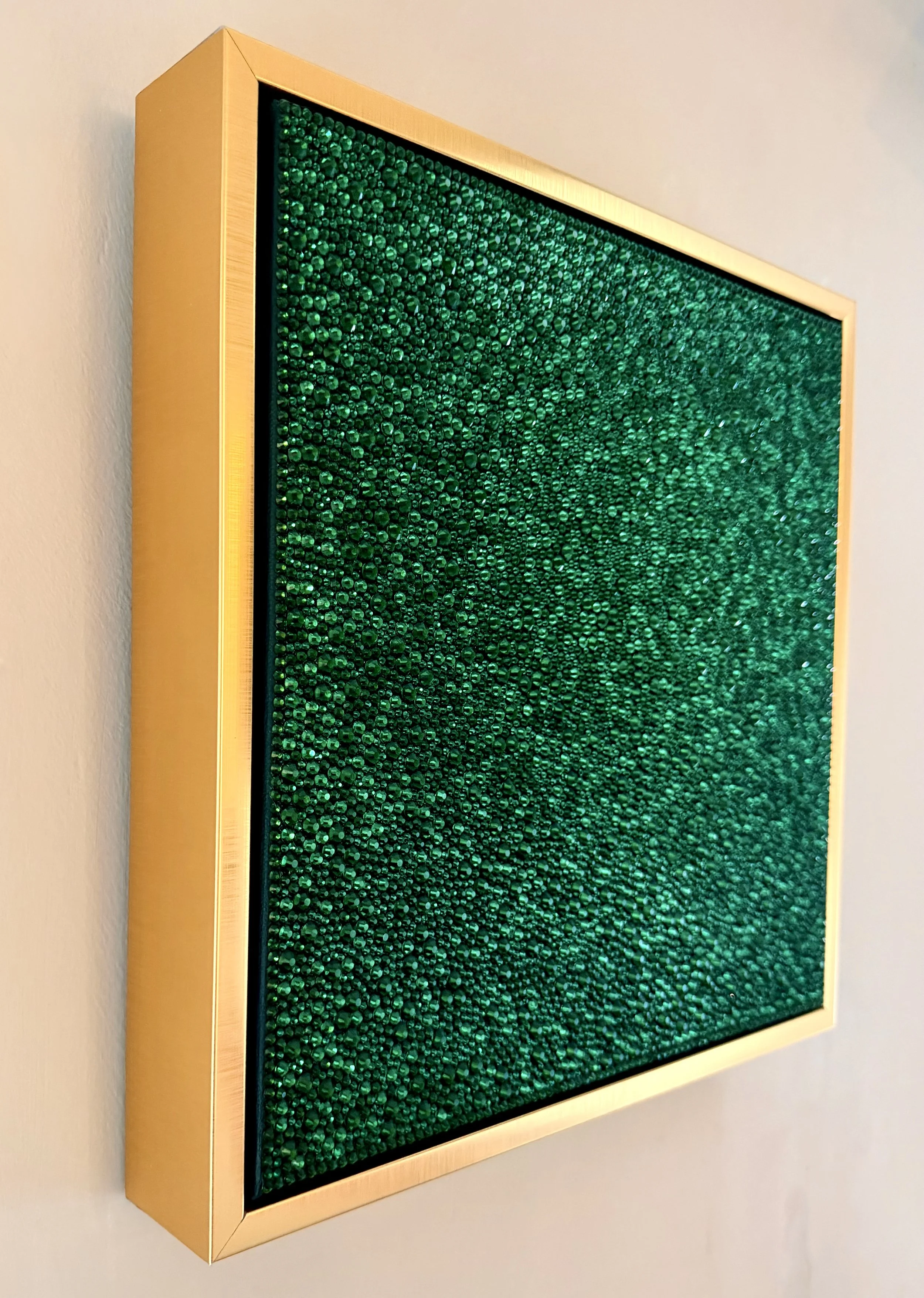 Side view of Greed (2026) showing the 3D texture of emerald rhinestones and the gold floating frame. Highlights the depth and sculptural profile.