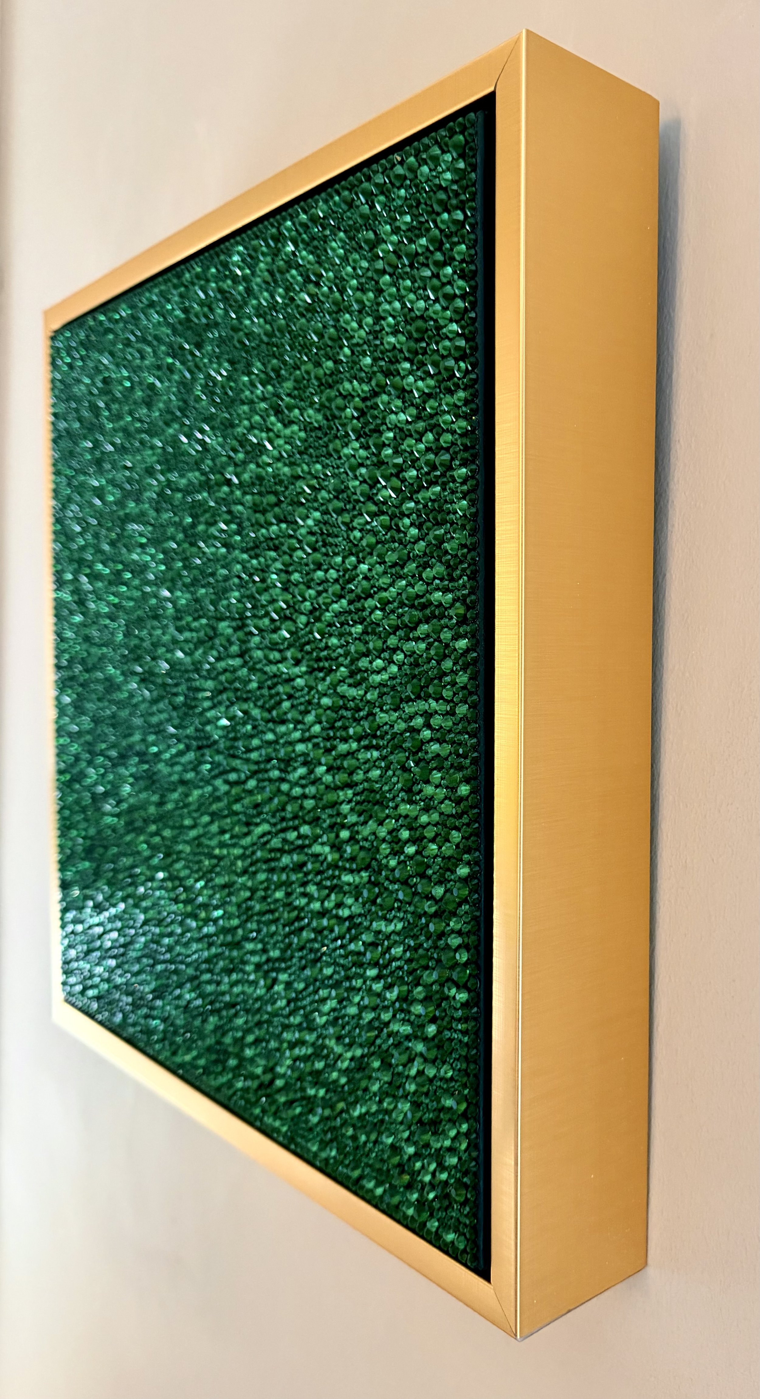 Side view of Greed (2026) showing the 3D texture of emerald rhinestones and the gold floating frame. Highlights the depth and sculptural profile.