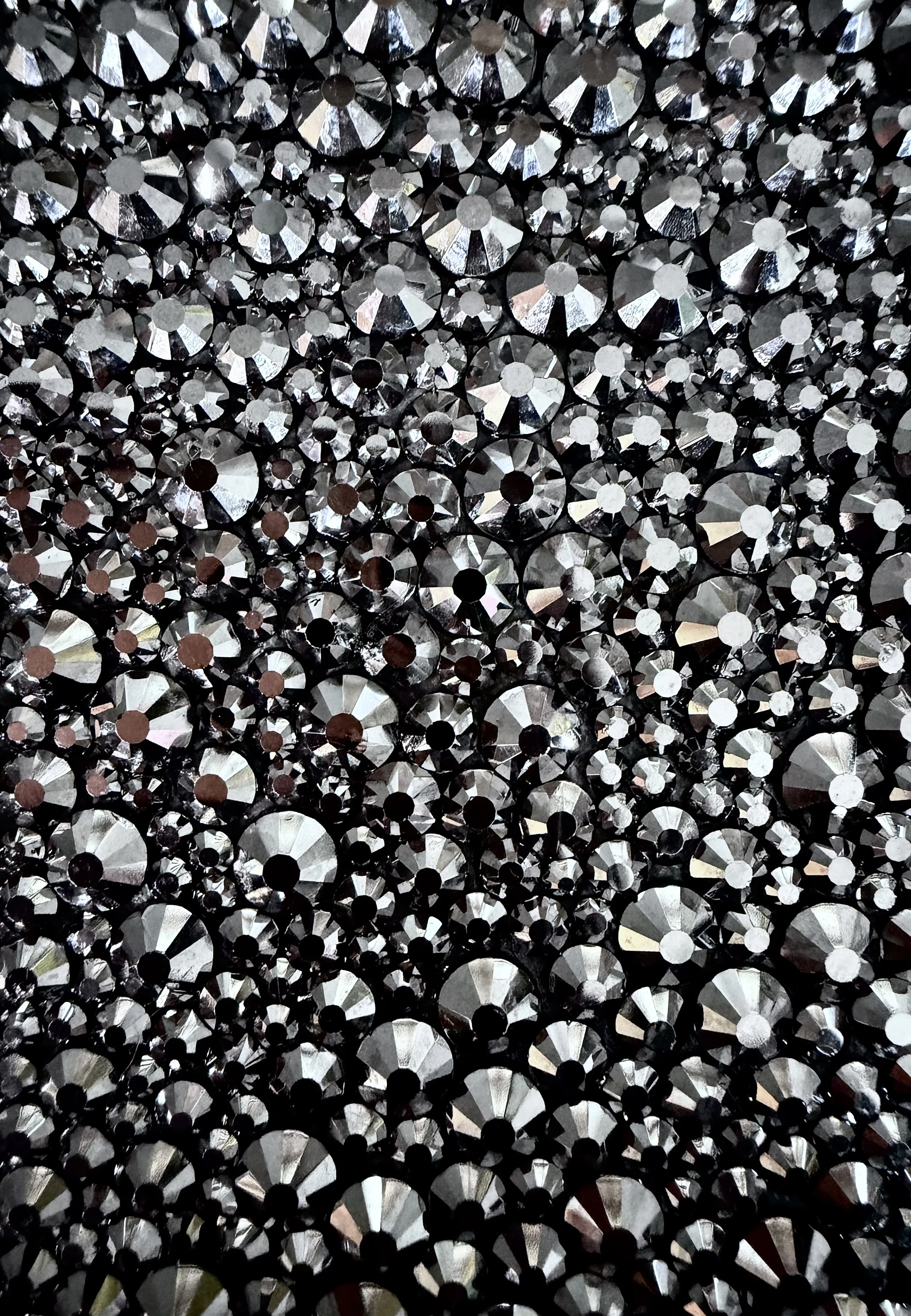 Macro detail of Sloth (2026). Close-up of faceted hematite glass rhinestones, showing the light-catching texture and dense, rhythmic placement.