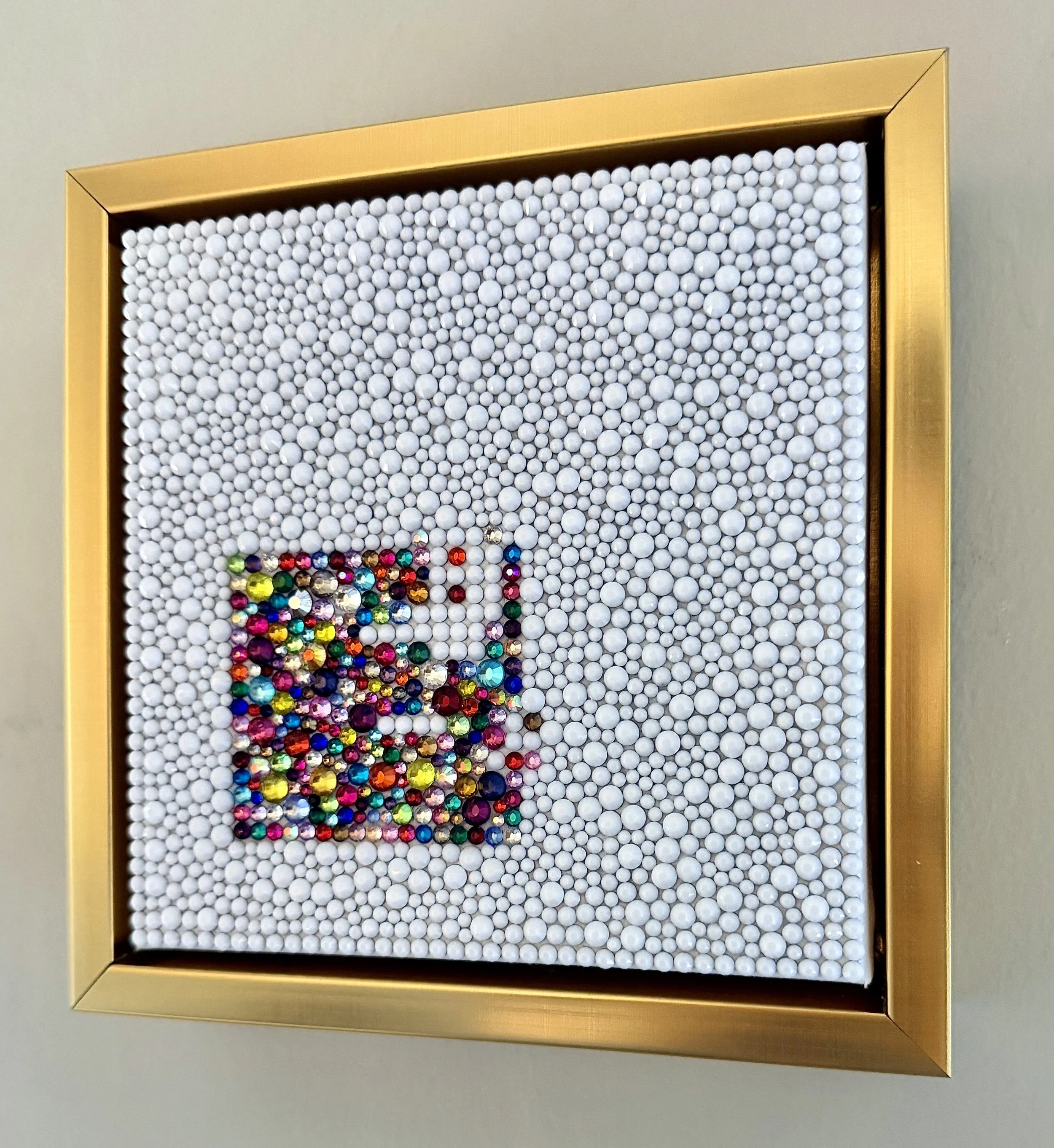 Angled side view of "Dread," showing the depth of the white beaded surface and the colorful rhinestone cluster within a gold floating frame.