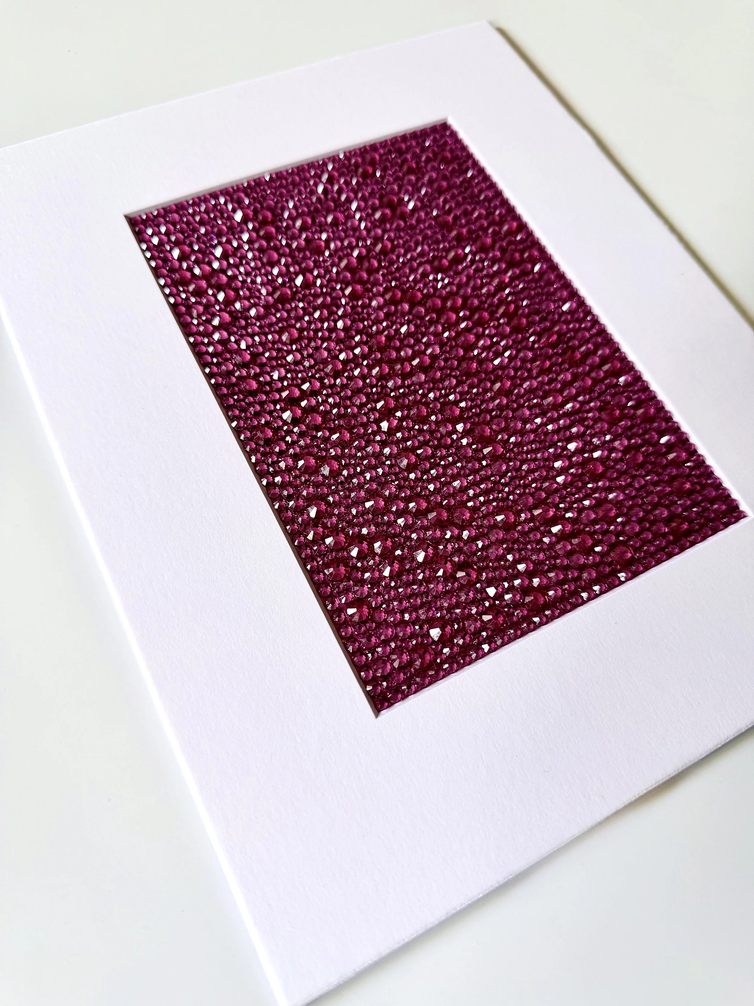 An angled close-up of the "Ache" paper study, showing the high-relief texture of the fuchsia rhinestone field.