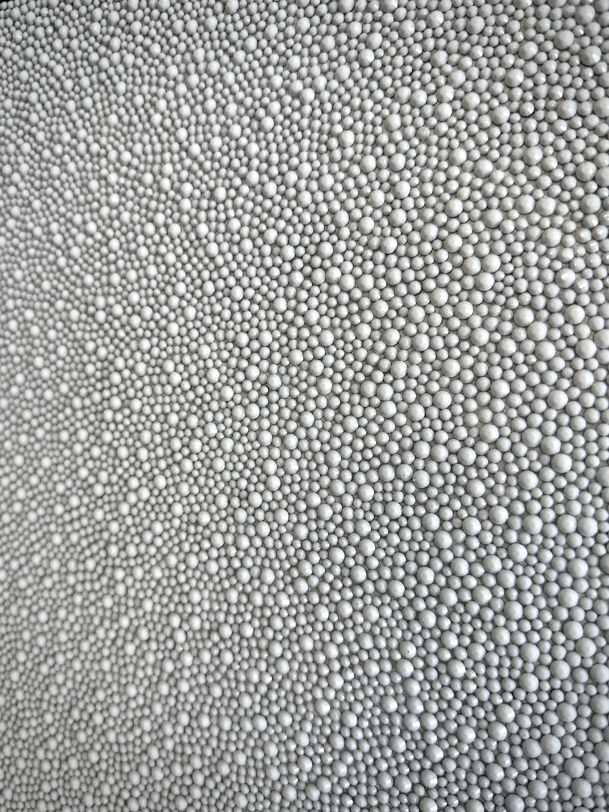 Macro detail of Flawless (2025). Close-up of faceted white glass rhinestones, creating a uniform, brilliant field of pure white light.