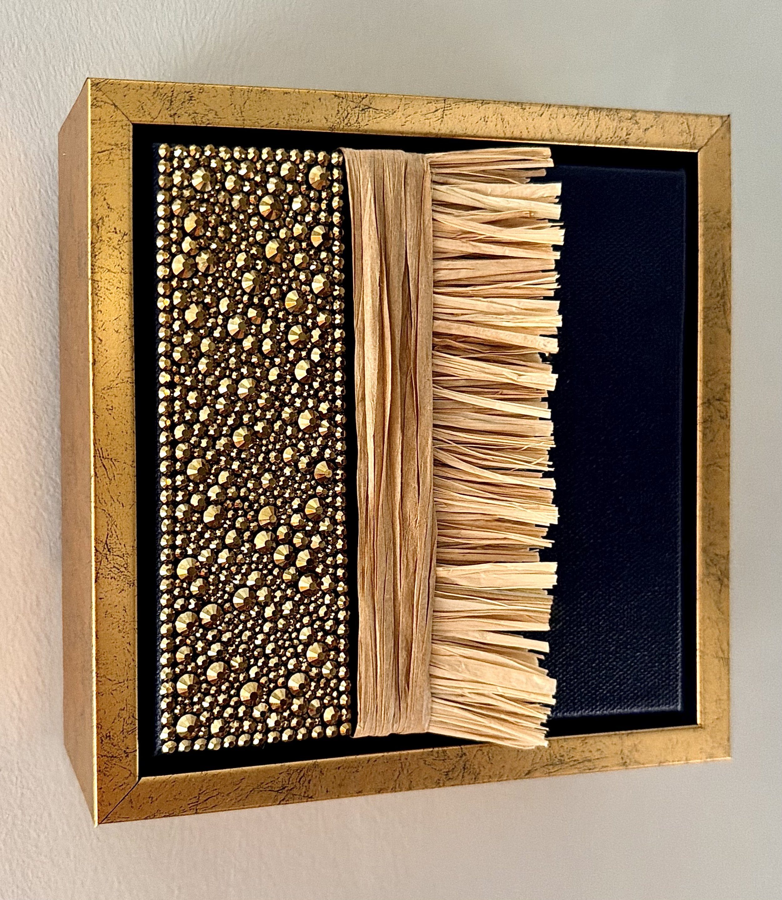 "Adrift" a 6x6 inch mixed-media piece of gold rhinestones and natural raffia in a distressed gold floating frame.