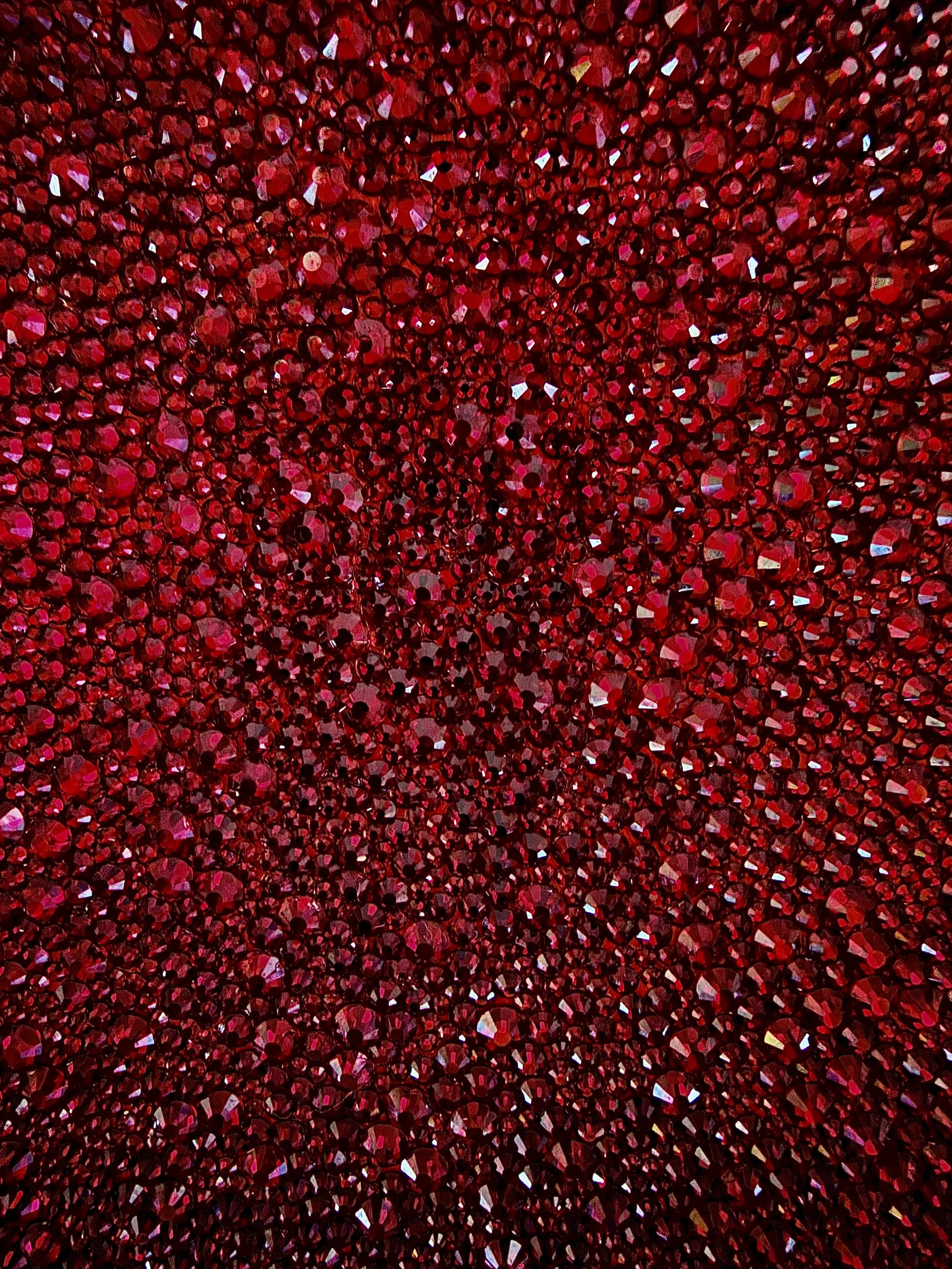 Macro detail of Wrath (2026). Close-up of faceted crimson glass rhinestones, showing the light-catching texture and dense, rhythmic placement.