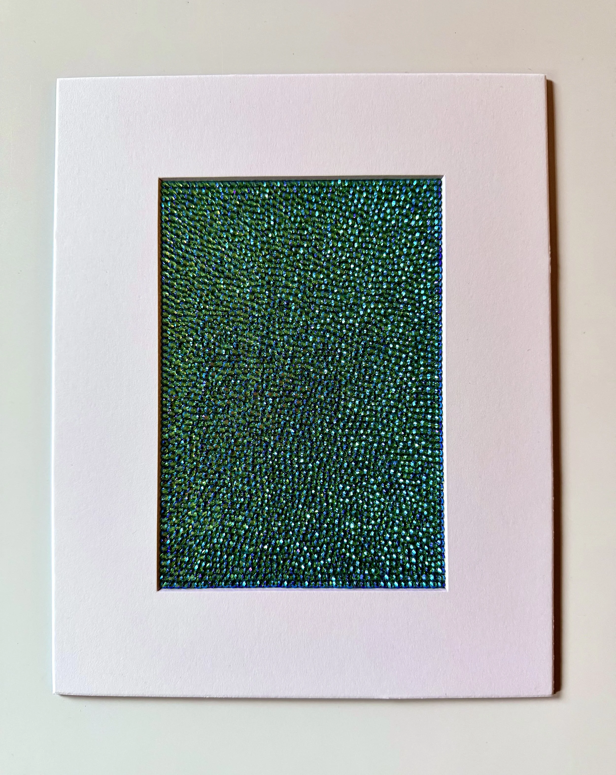 Hollow, 2026. 5 x 7 in. [matted to 8 x 10 in.] A dense, shimmering field of peridot ab glass rhinestones on watercolor paper, presented within a clean white mat.