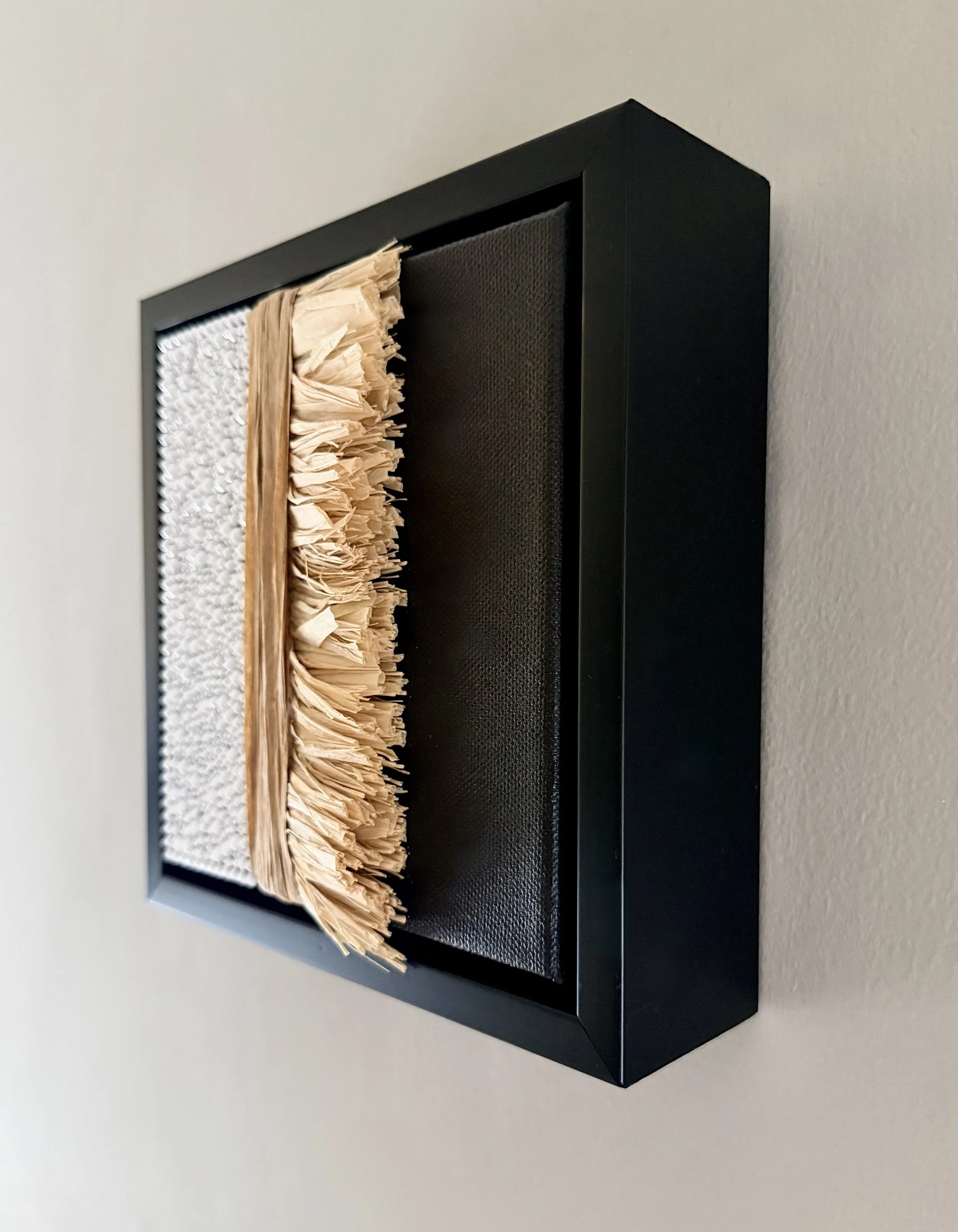 A profile image of "Anxiety" a 6x6 inch mixed-media piece of white rhinestones and natural raffia in a black floating frame.