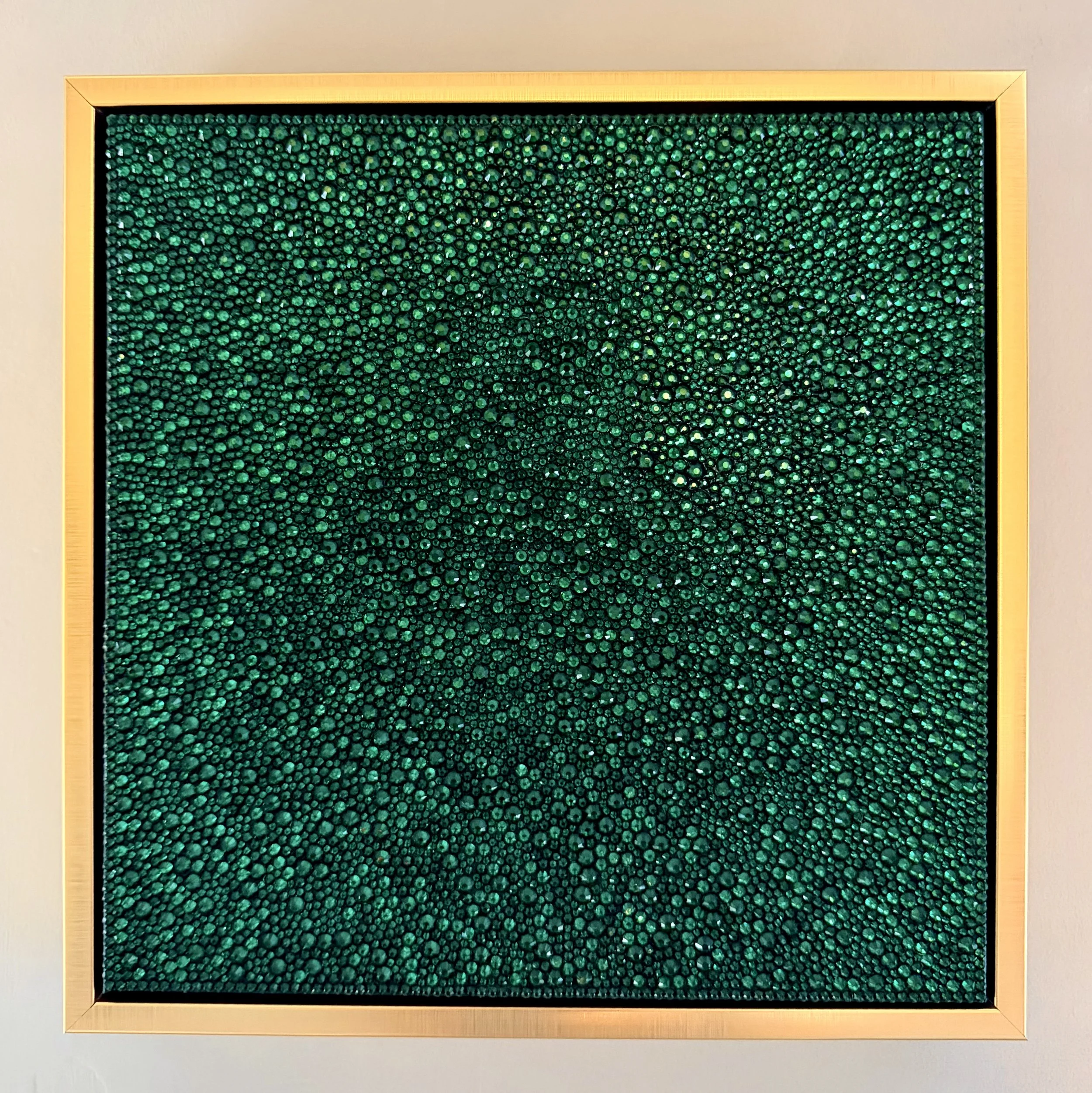 Greed (2026). 12x12 in. sculptural panel in a gold frame. Features hand-placed emerald glass rhinestones in a vibrant, monochromatic field.