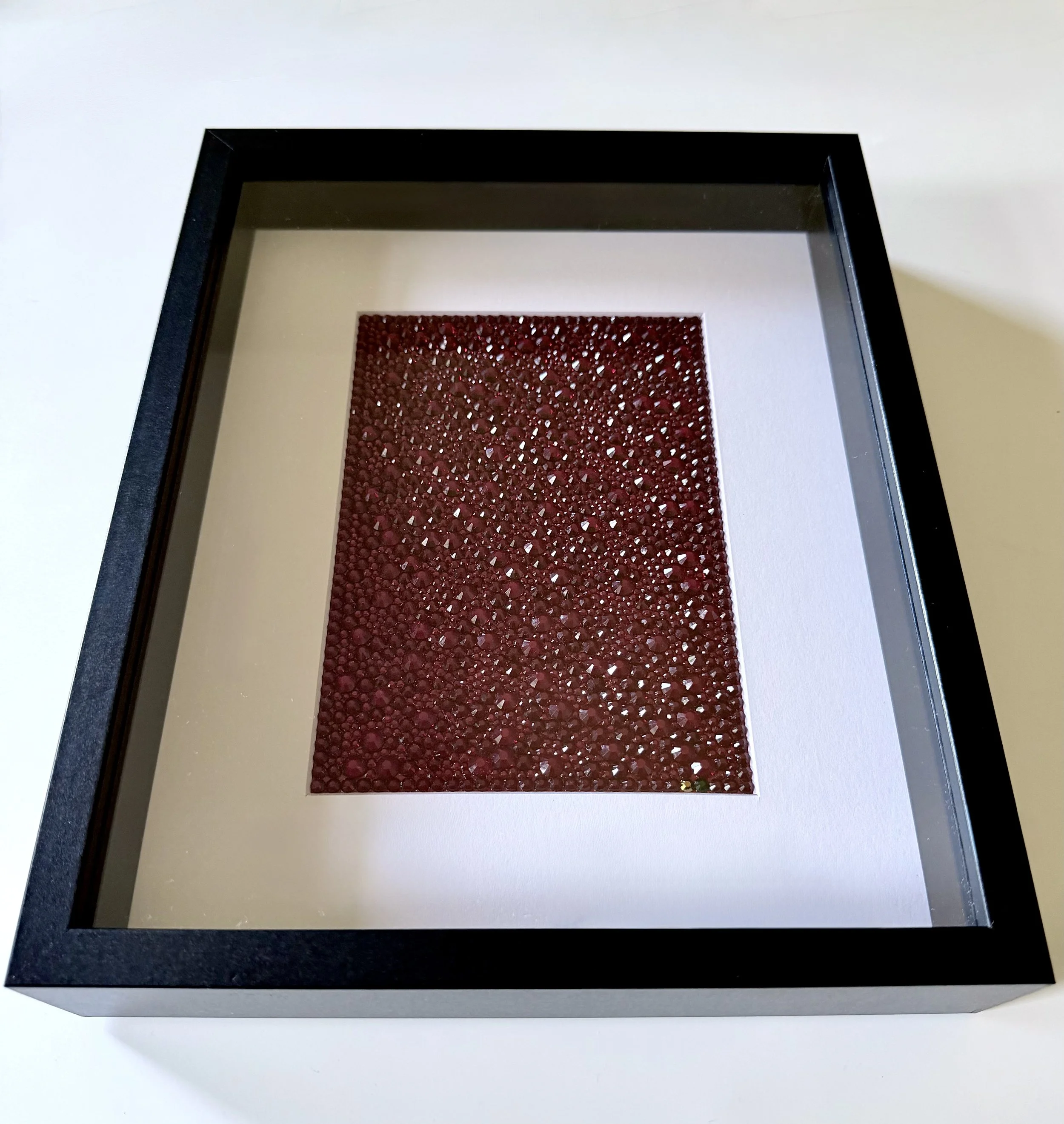 Framed crimson rhinestone art piece titled "Convergence."