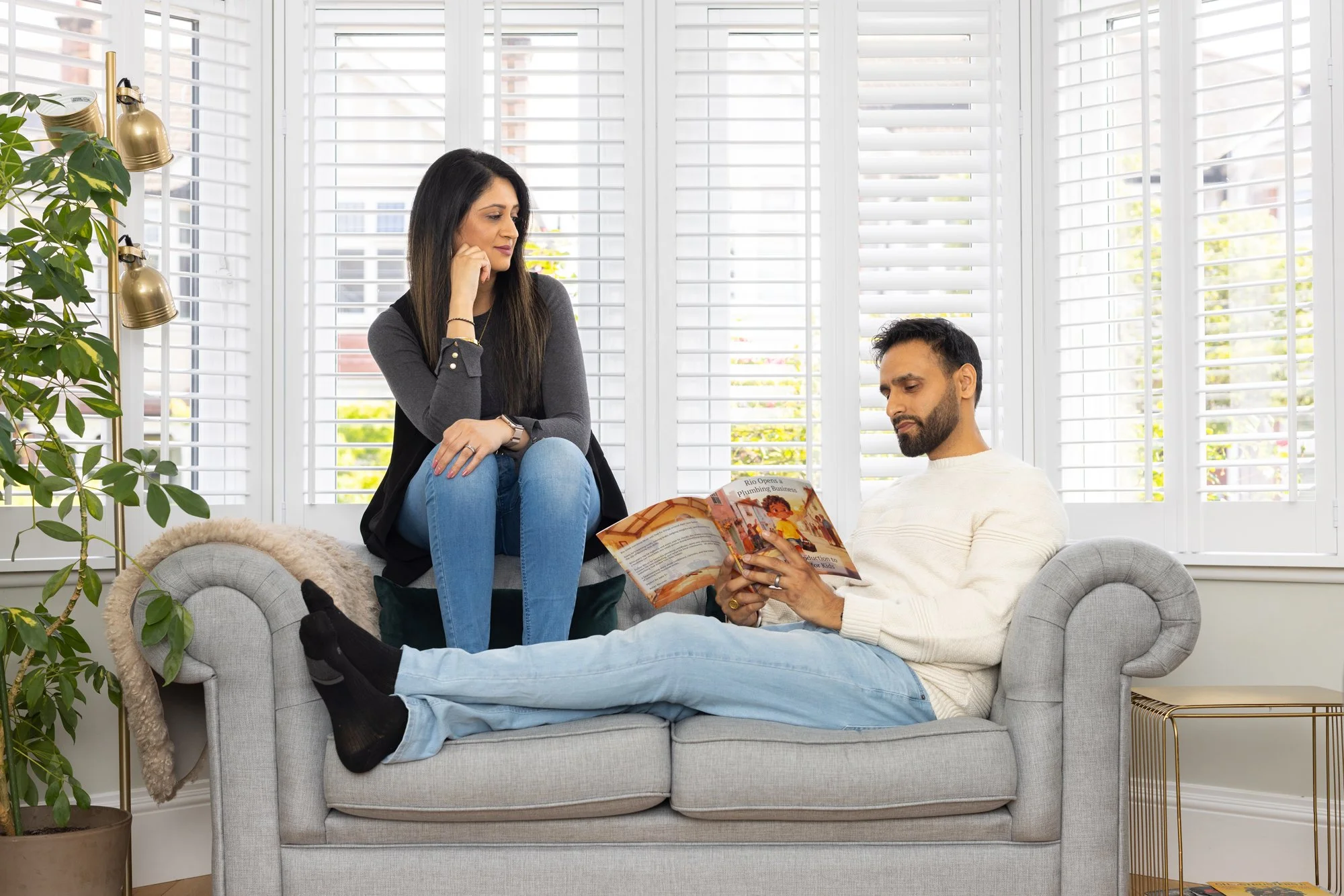 Sanjeev and Sonia on a sofa reading a Rebel Rio book