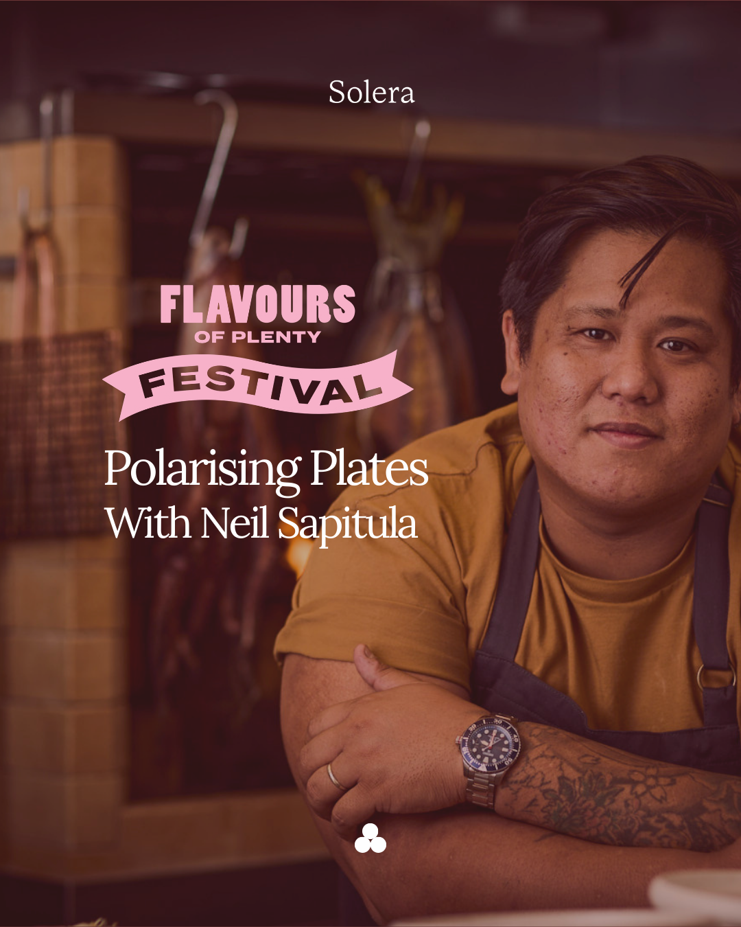 A man with tattoos wearing a gold shirt and a black apron, leaning on a counter in a kitchen. Text overlays: 'Flavours of Plenty Festival', 'Polarising Plates with Neil Sapitula.'