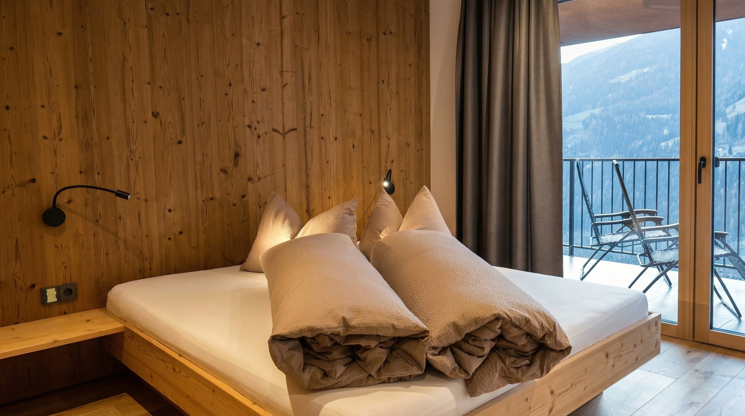 Schlafzimmer in den Lahnerhof Chalets, Wände mit Holzverkleidung, Doppelbett im Fokus
