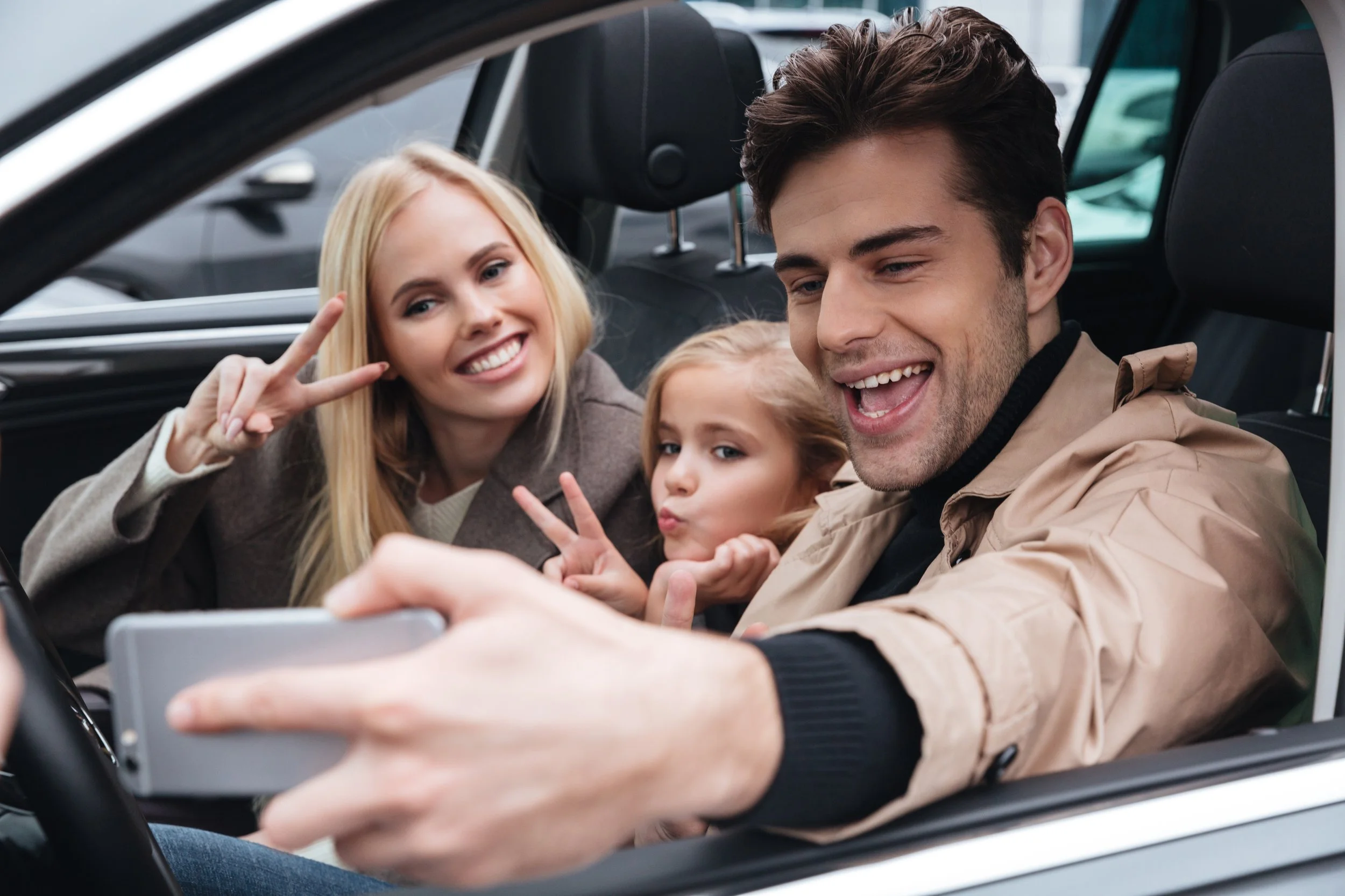 Família sorridente fazendo selfie dentro do carro