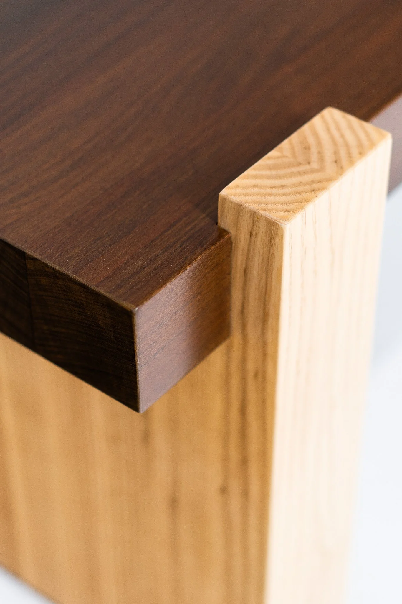 Close-up of a wooden furniture piece showing a dark brown tabletop and a light-colored vertical support panel.