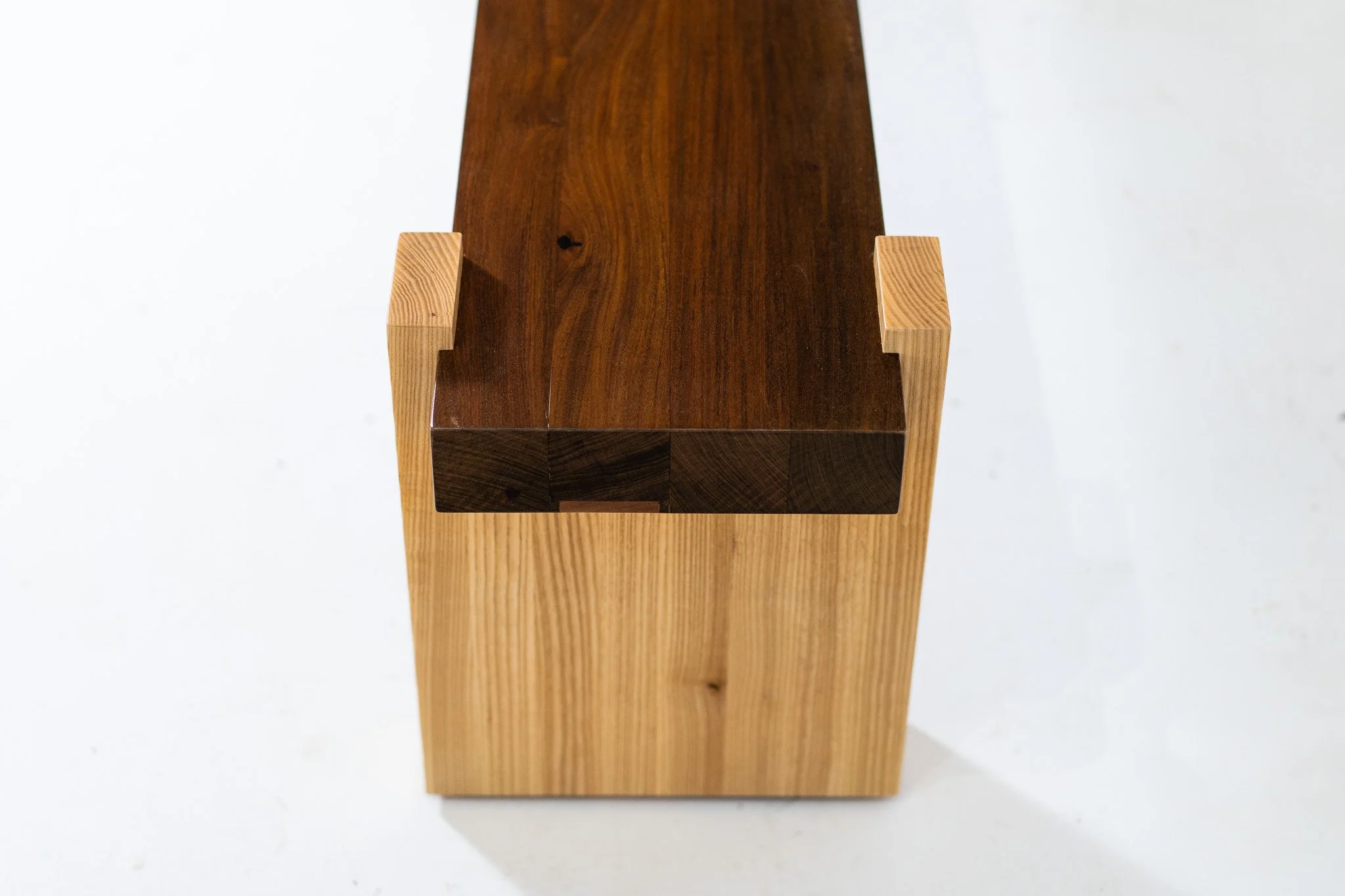 A wooden furniture piece with a dark top and lighter legs, viewed from above.