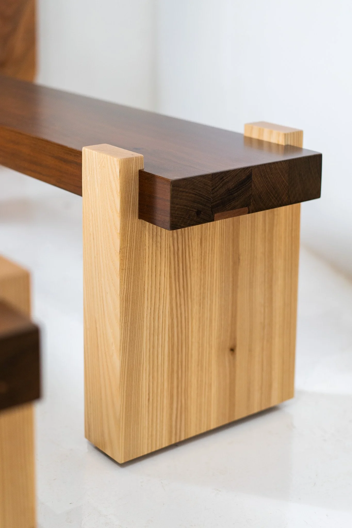 Close-up of a modern wooden furniture piece, combining light and dark wood, with a sleek minimalist design.