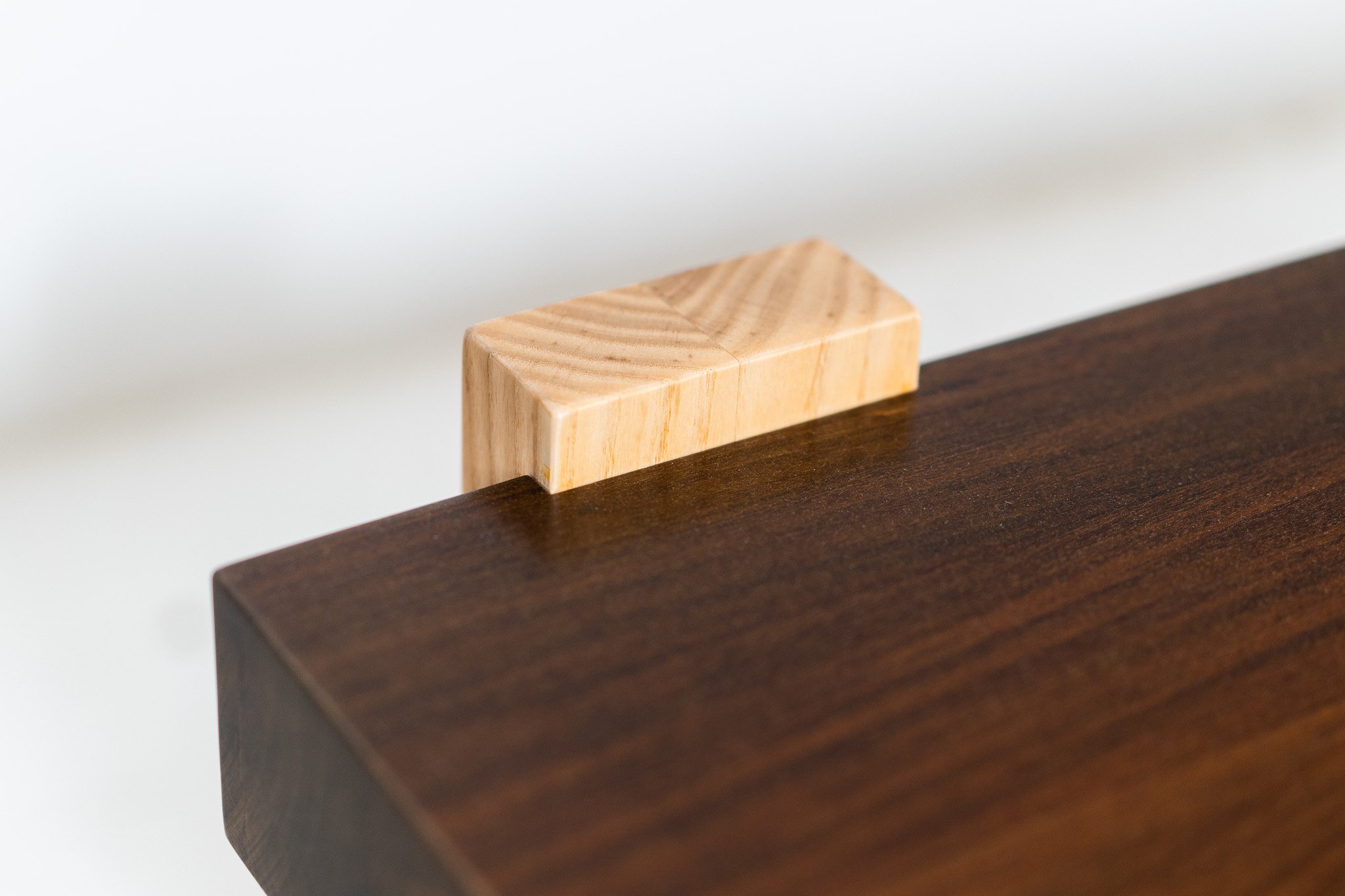 Close-up of a wooden table with a small, light-colored wooden block resting on the edge.