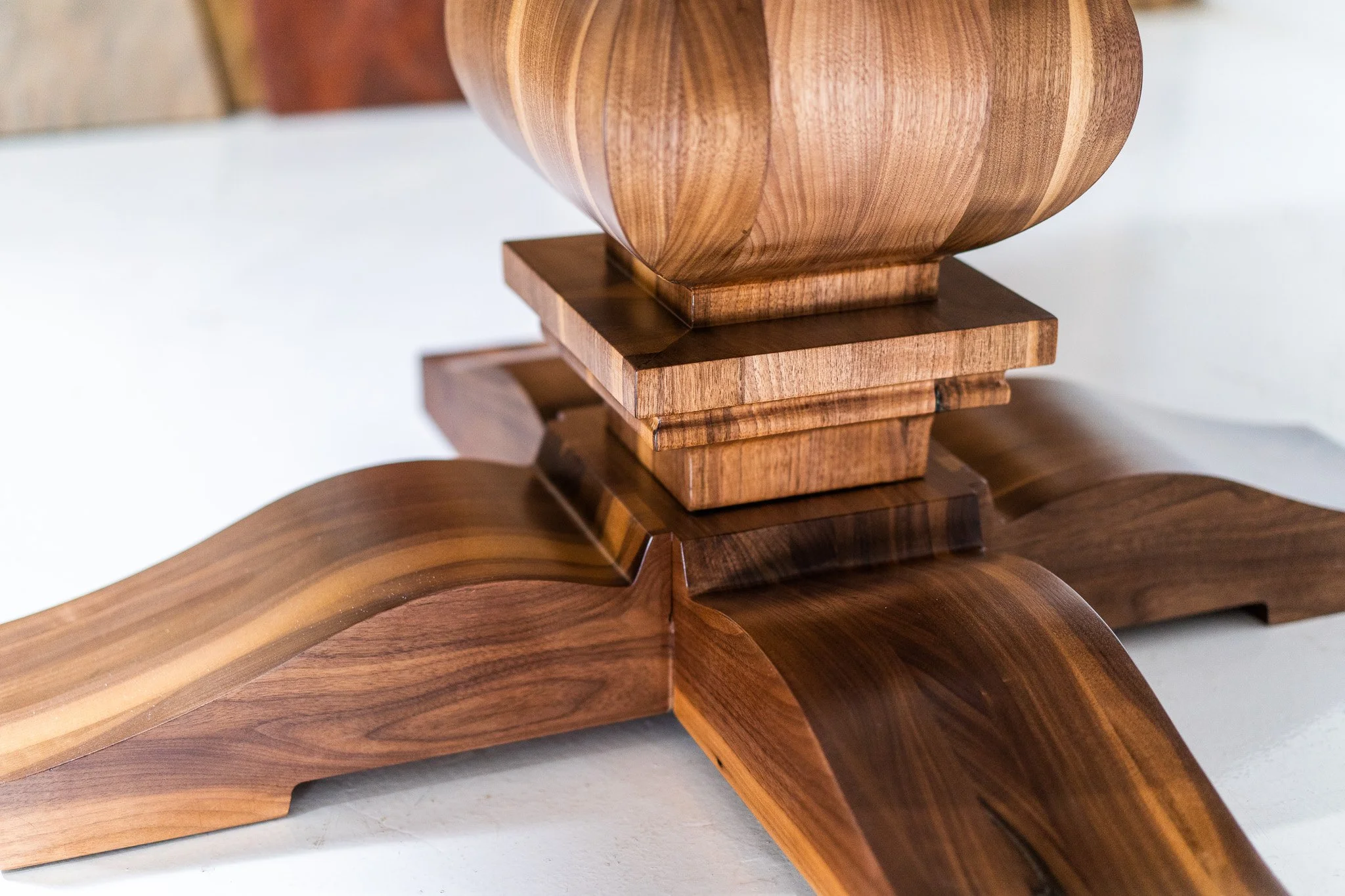 Close-up of a wooden sculpture with a rounded top, set on a base with layered square platforms, all crafted from polished wood with visible grain patterns.