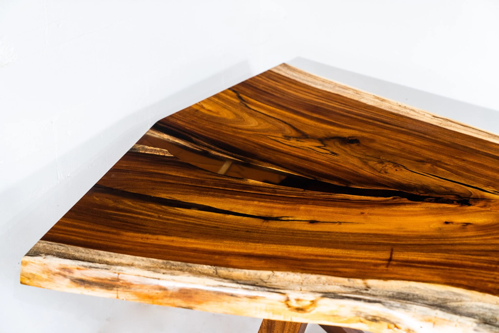 Close-up of a wooden table with a natural, rustic finish, positioned against a white wall with minimal decor.